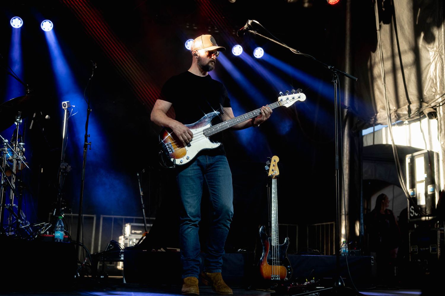 Band performs on dimly lit stage with electric guitar and stage lighting.
