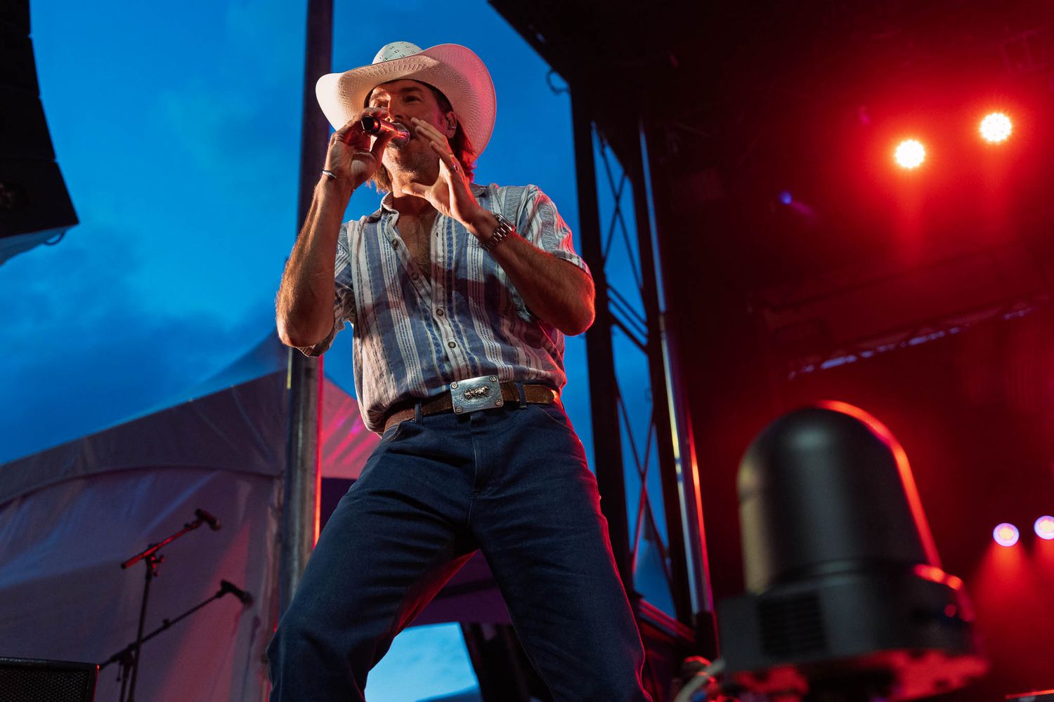 Musicians for country band Midland perform under dramatic red and blue stage lighting at outdoor concert.