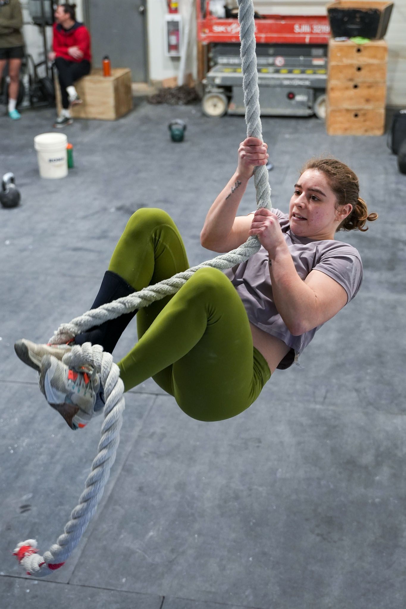 Person demonstrating advanced gymnastics moves on rings in a CrossFit gym setting.