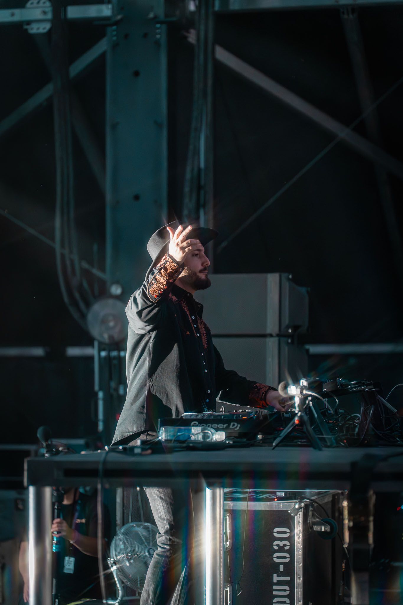 DJ Alesso performing at a dark venue with professional equipment and dramatic lighting.