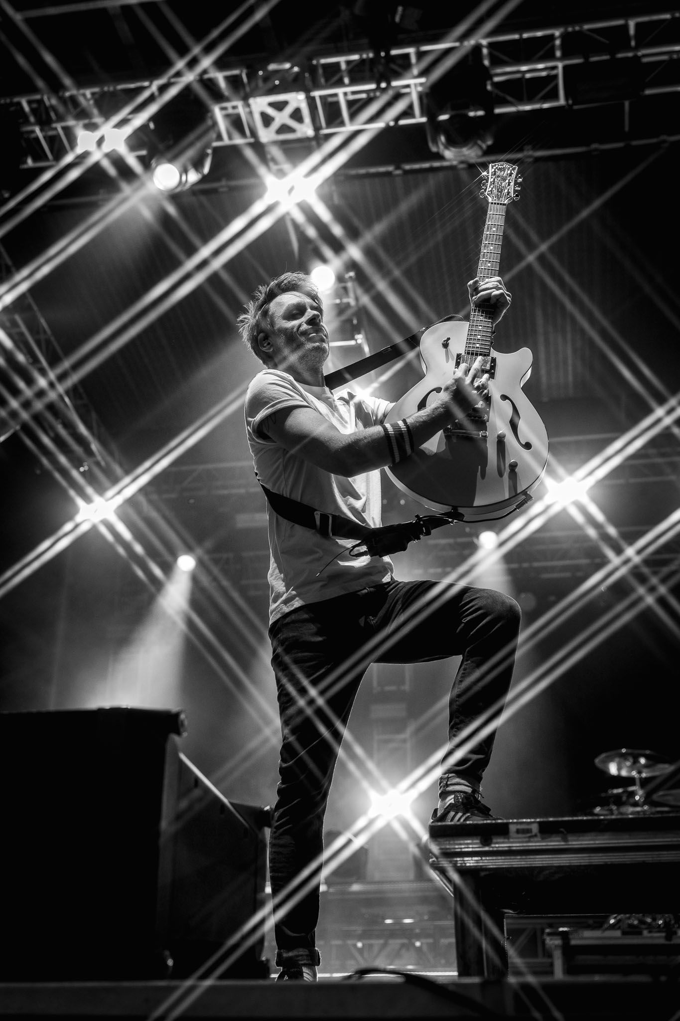 Black and white concert photo capturing dynamic performance with dramatic stage lighting.