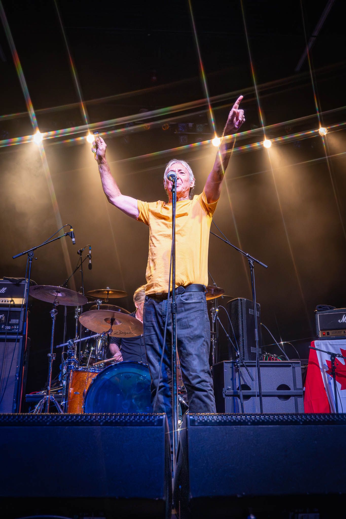 Performer on elevated stage with bright overhead lighting during concert.