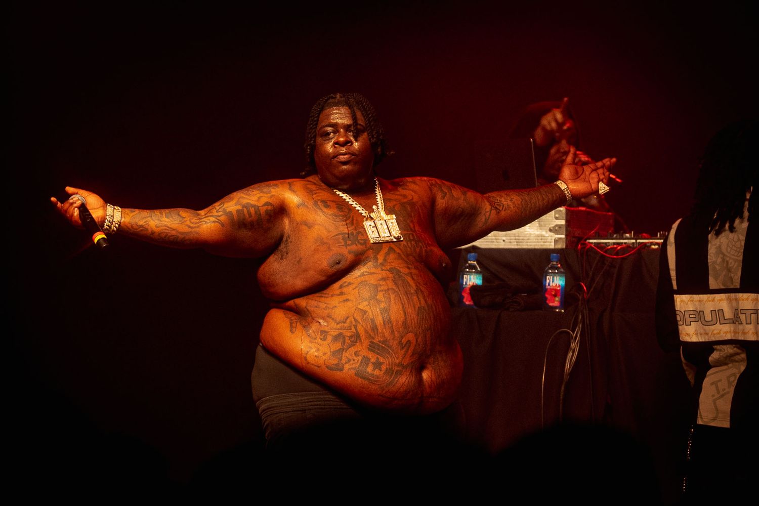 Silhouetted hip-hop artist BigXthaPlug on stage with dramatic red backlighting during show.