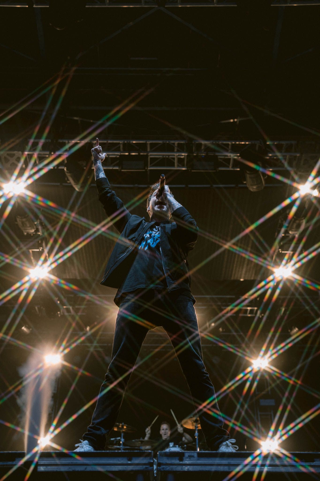 Simple Plan concert performance with starburst lighting effects and silhouetted performer.