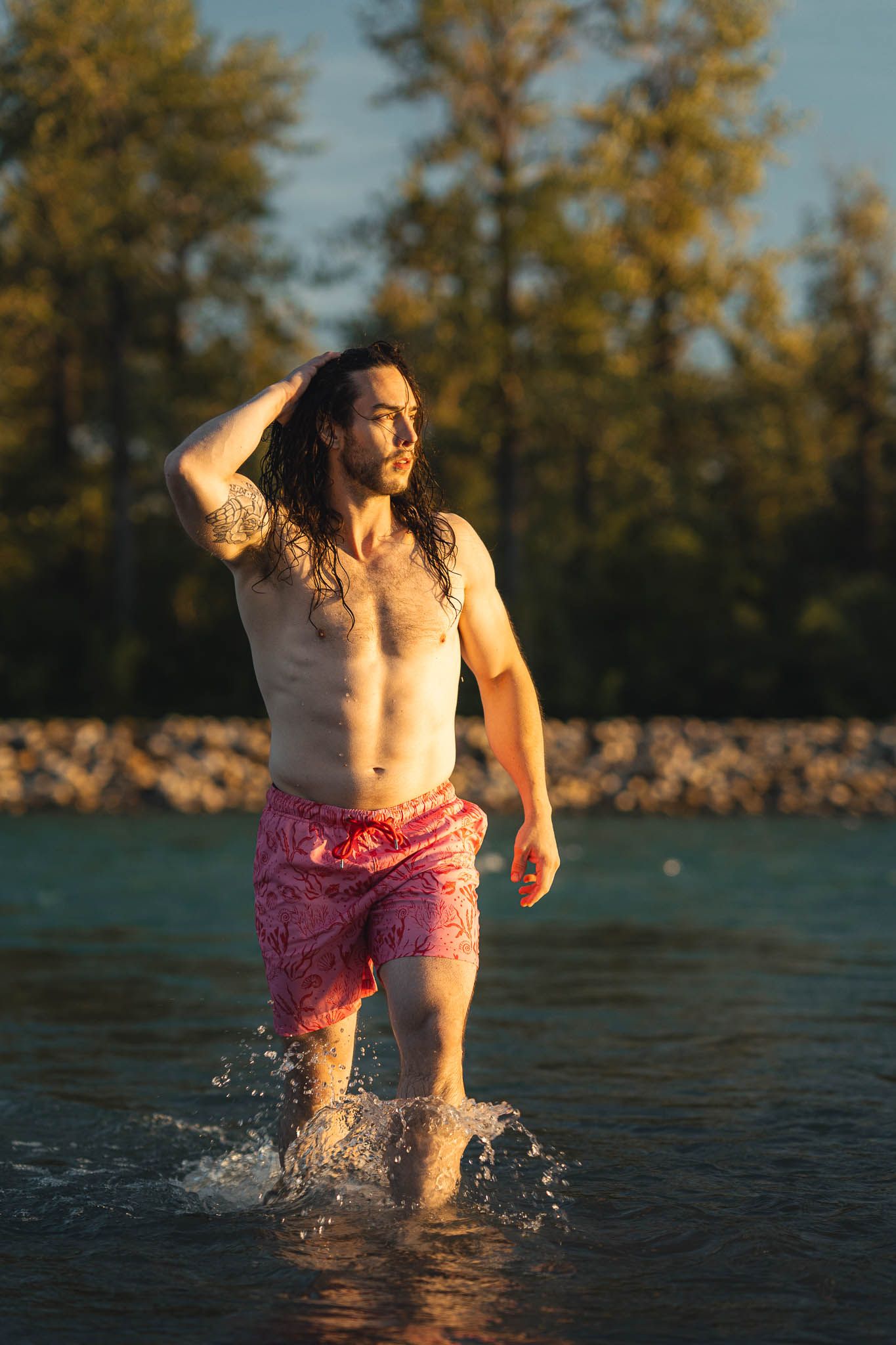 Person splashing through shallow water at sunset wearing pink shorts.