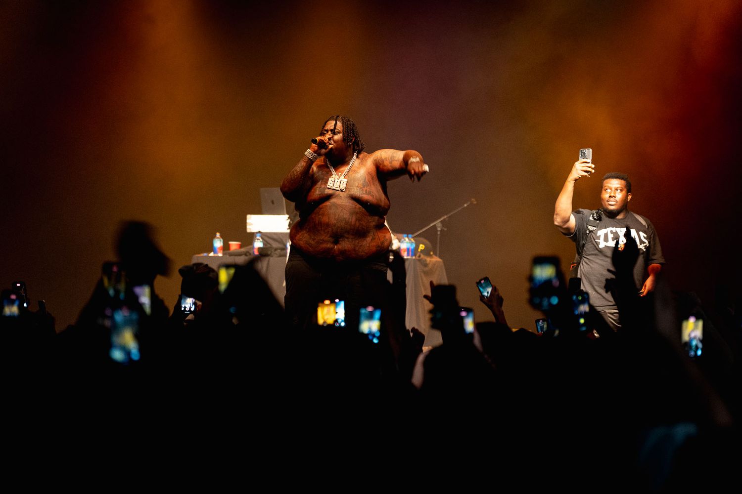 BigXthaPlug energetically engaging with crowd under dramatic orange stage lighting.