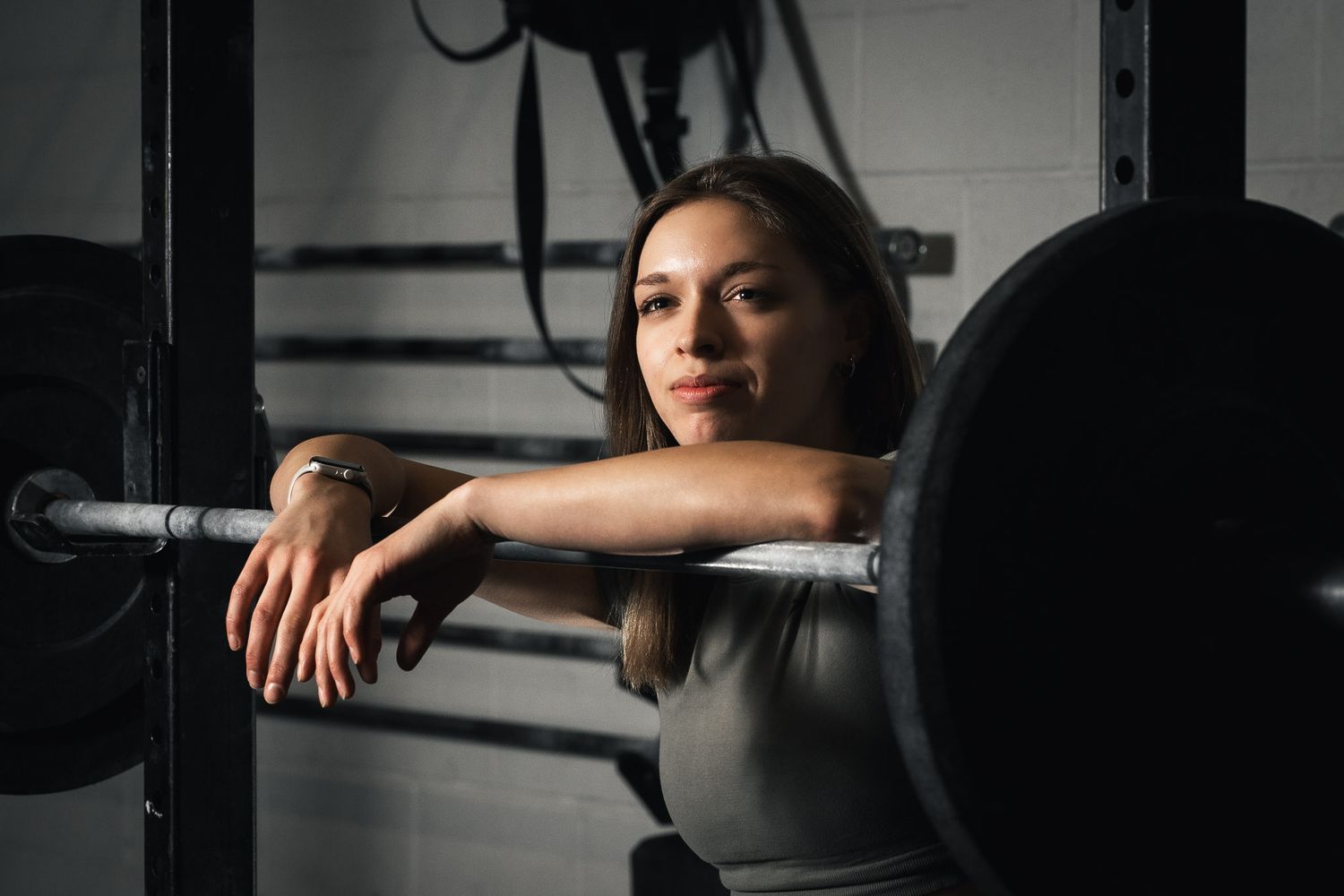 Silhouettes of people exercising with gym equipment in a dimly lit fitness space.