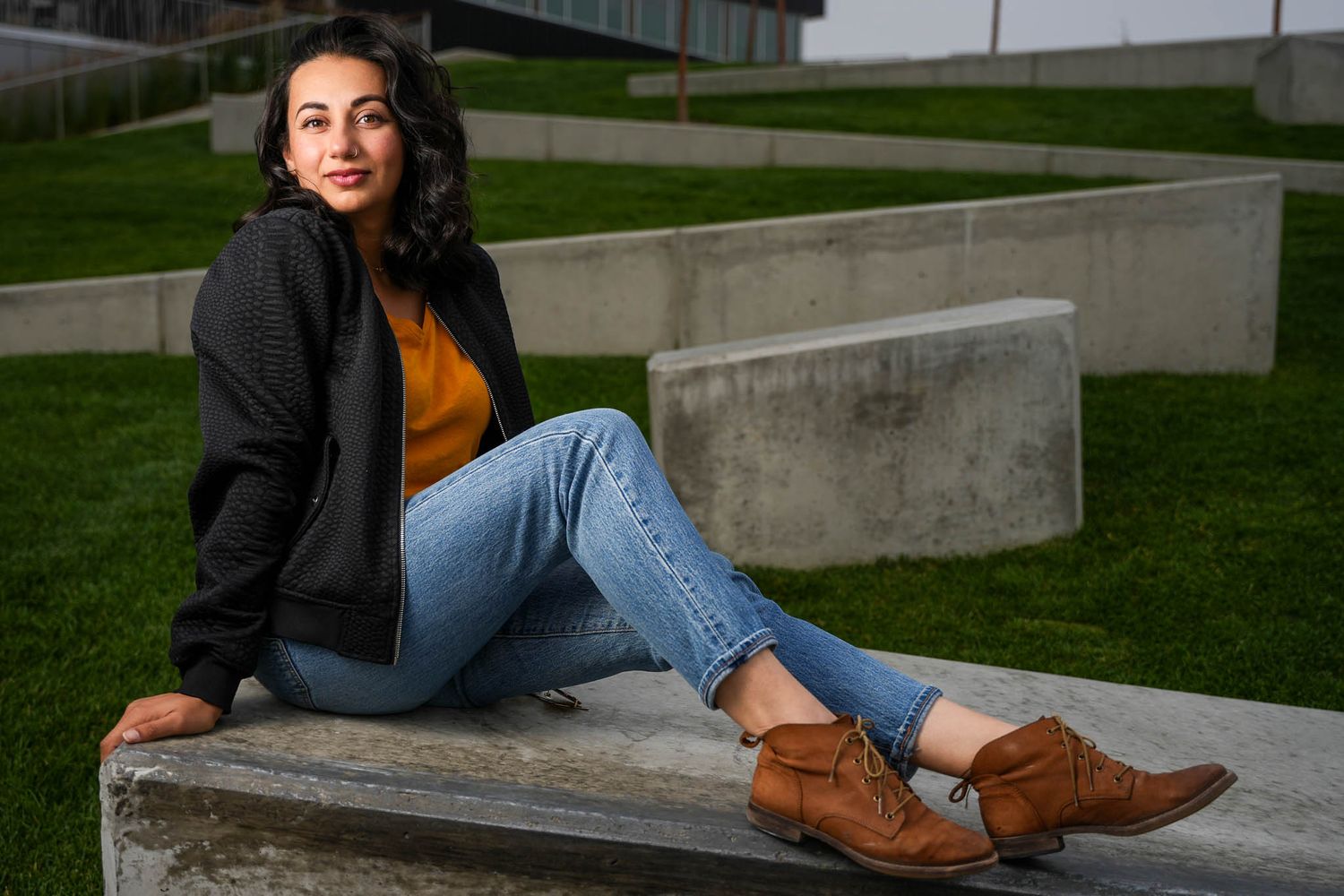 Casual autumn look with black jacket and jeans while sitting on concrete steps.
