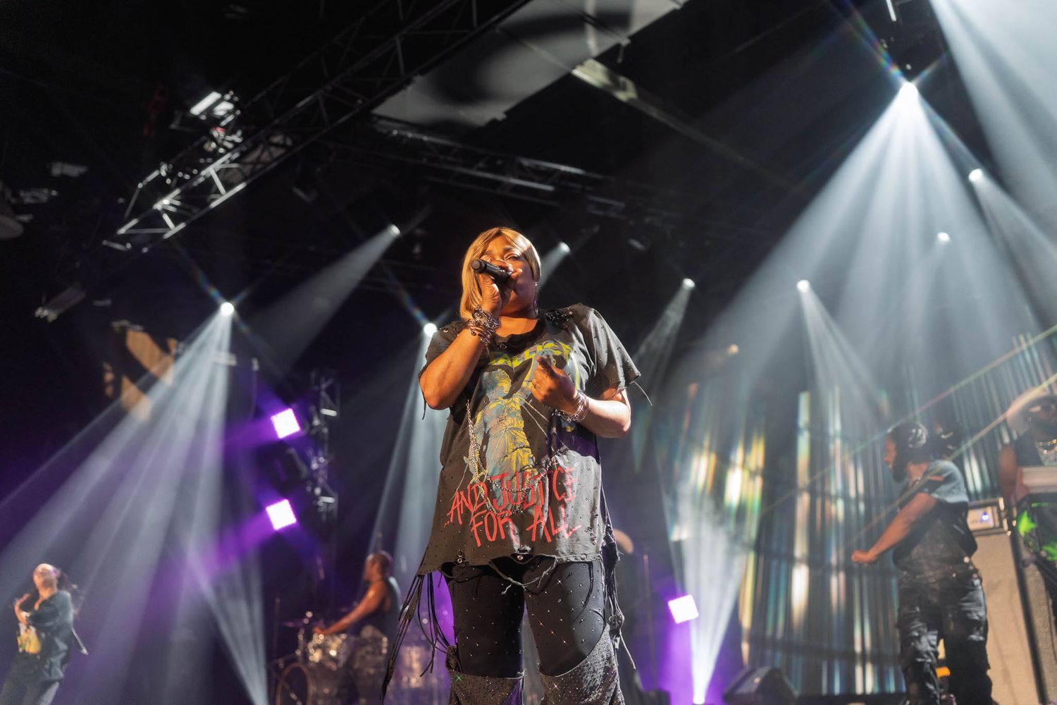 TLC performs on stage with dramatic lighting and spotlights creating an energetic atmosphere.