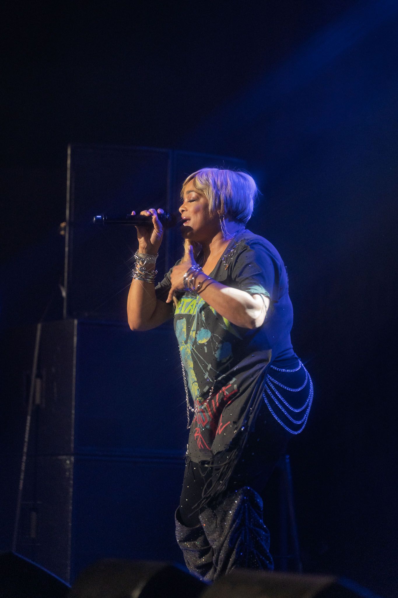 Singer performs with intense emotion under blue stage lights during live concert.
