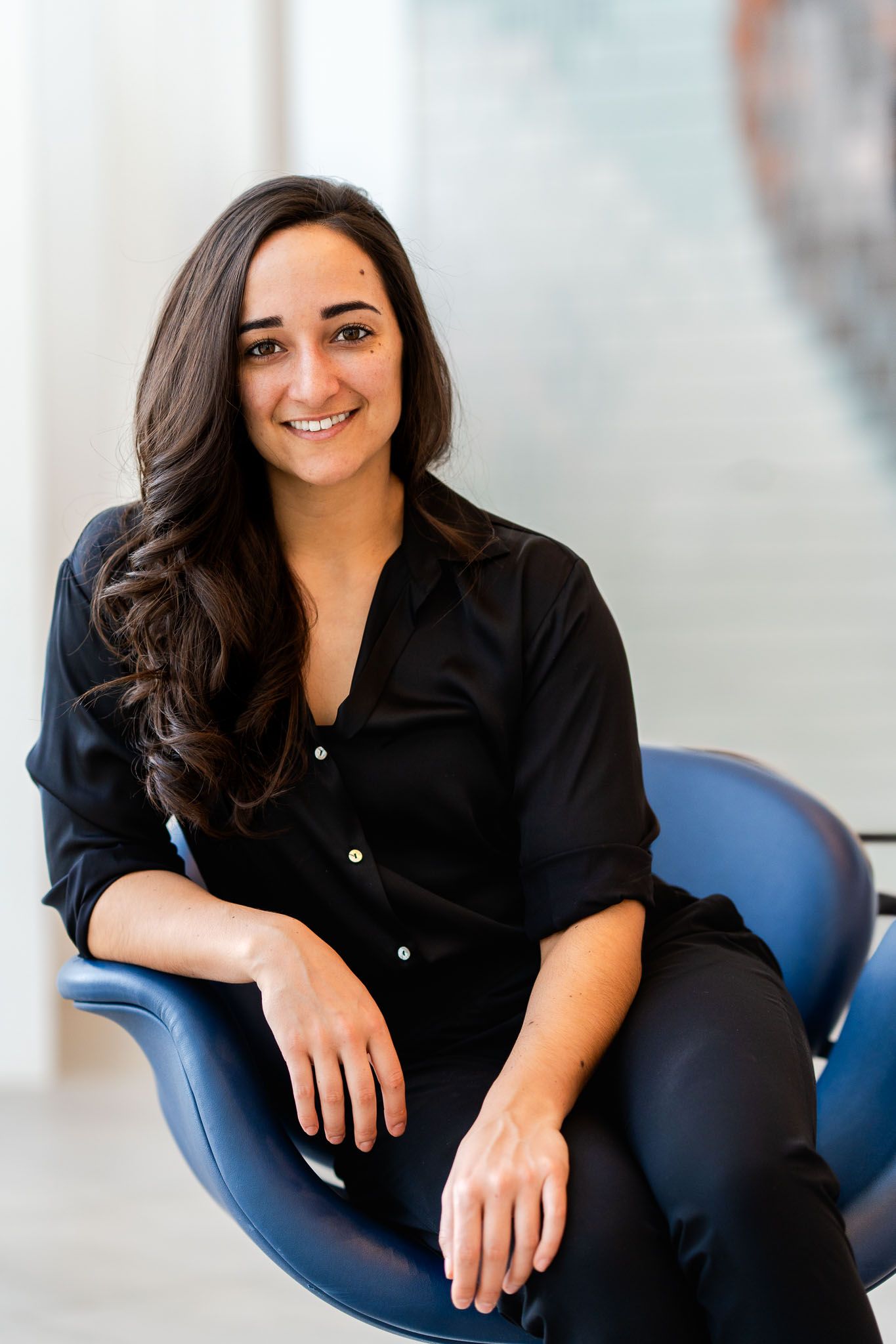 Person in dark shirt sits comfortably in blue chair during professional photoshoot.