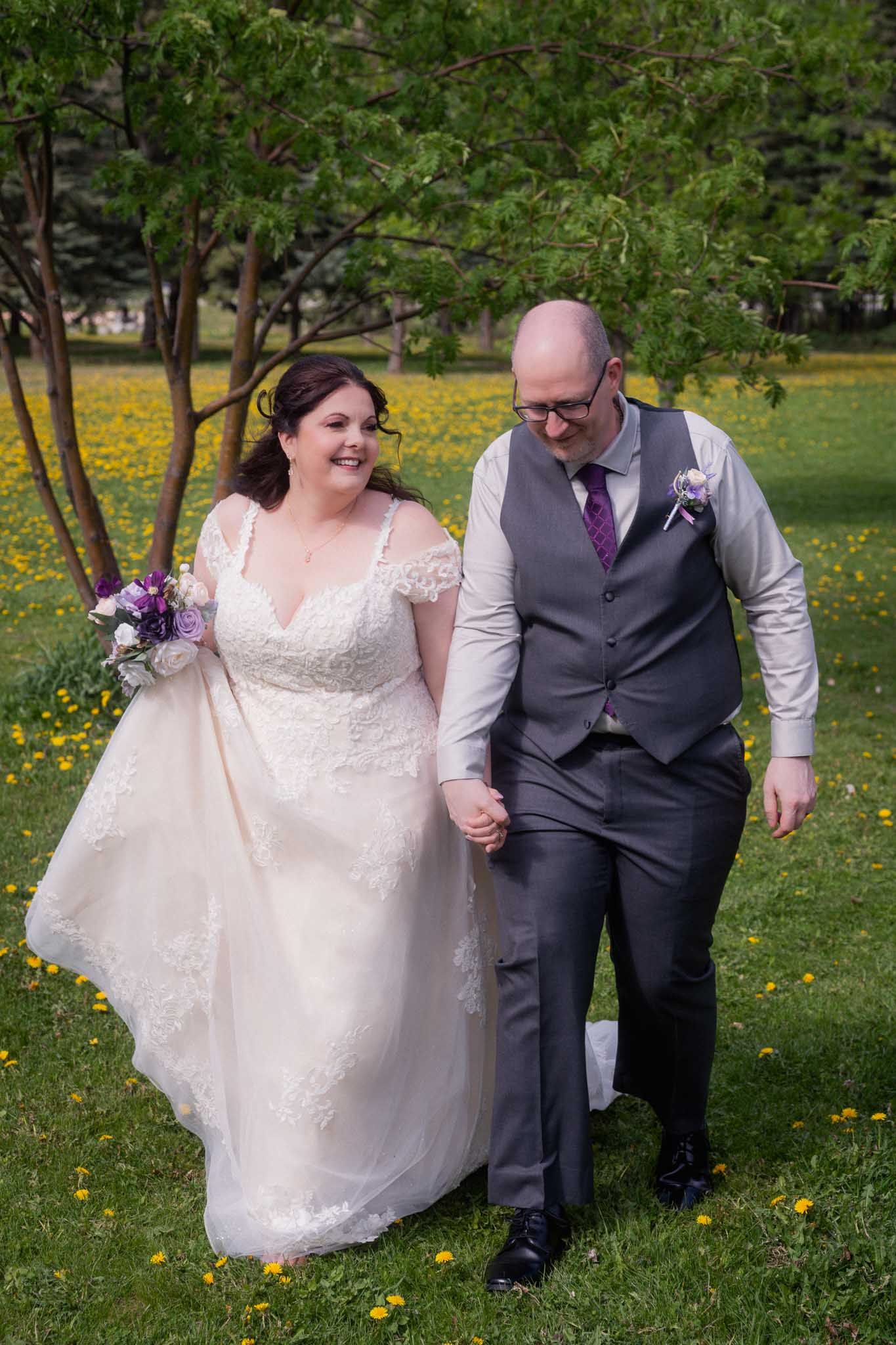 Couple walks hand in hand through a spring garden filled with yellow wildflowers.