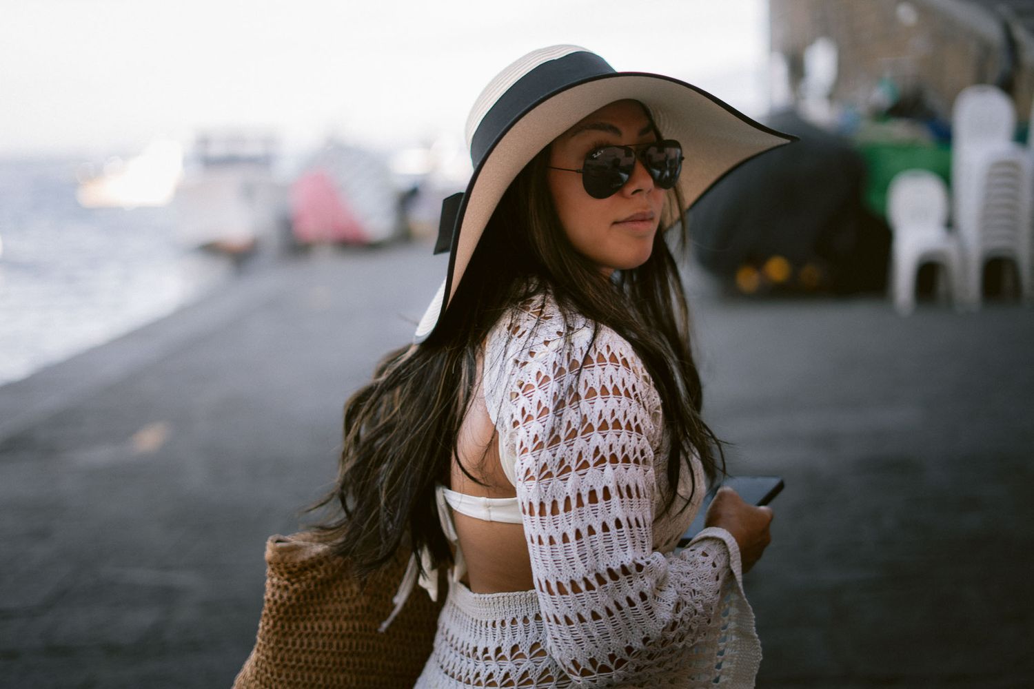 Summer beach style with crochet cover-up, sun hat, and woven bag against coastal Sorrento backdrop in italy
