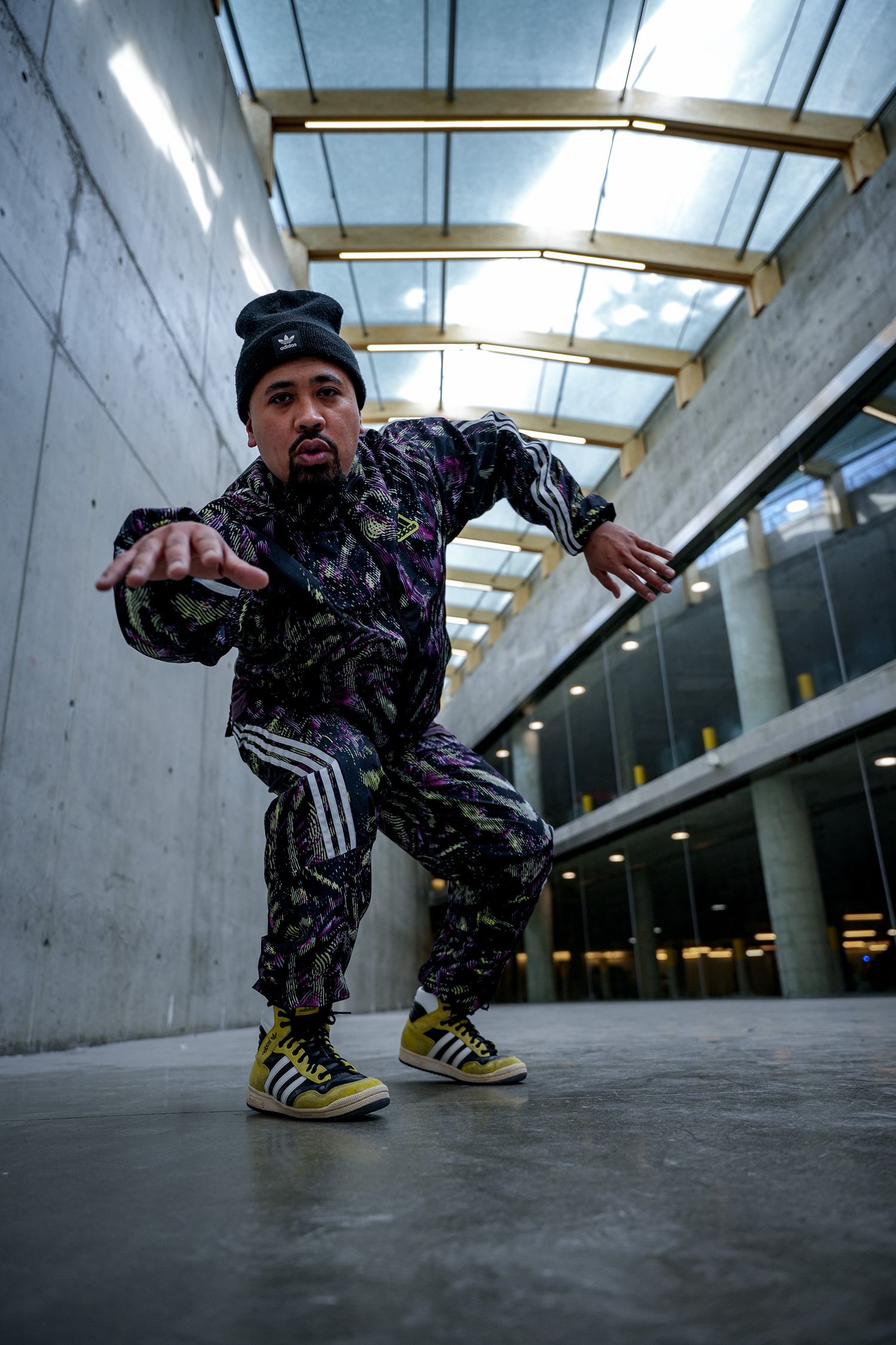 Street dancer in camouflage outfit demonstrates ground moves in industrial hallway.