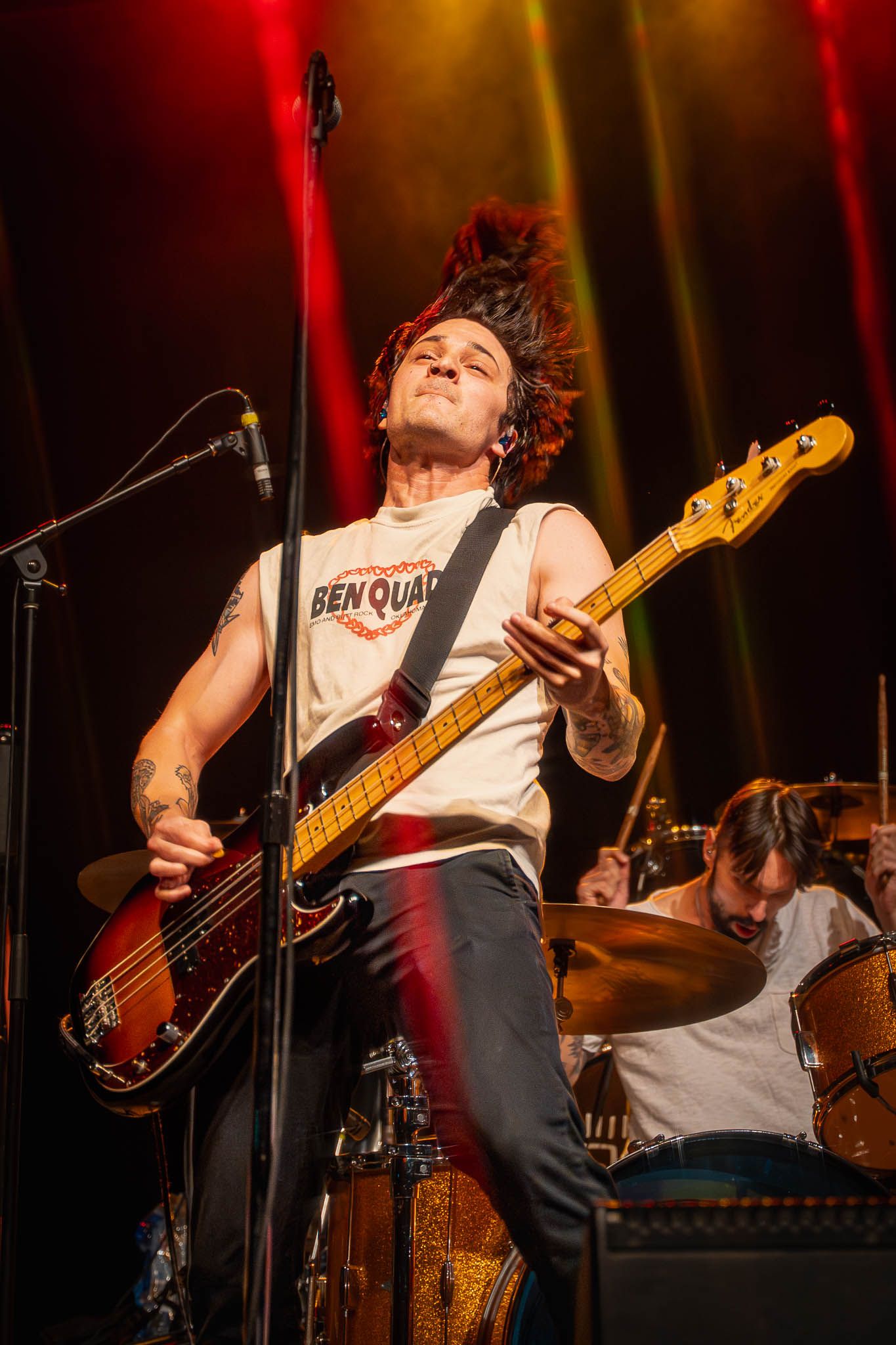 Energetic Mattstagraham performance under red and yellow stage lights with bass guitar and dramatic poses.