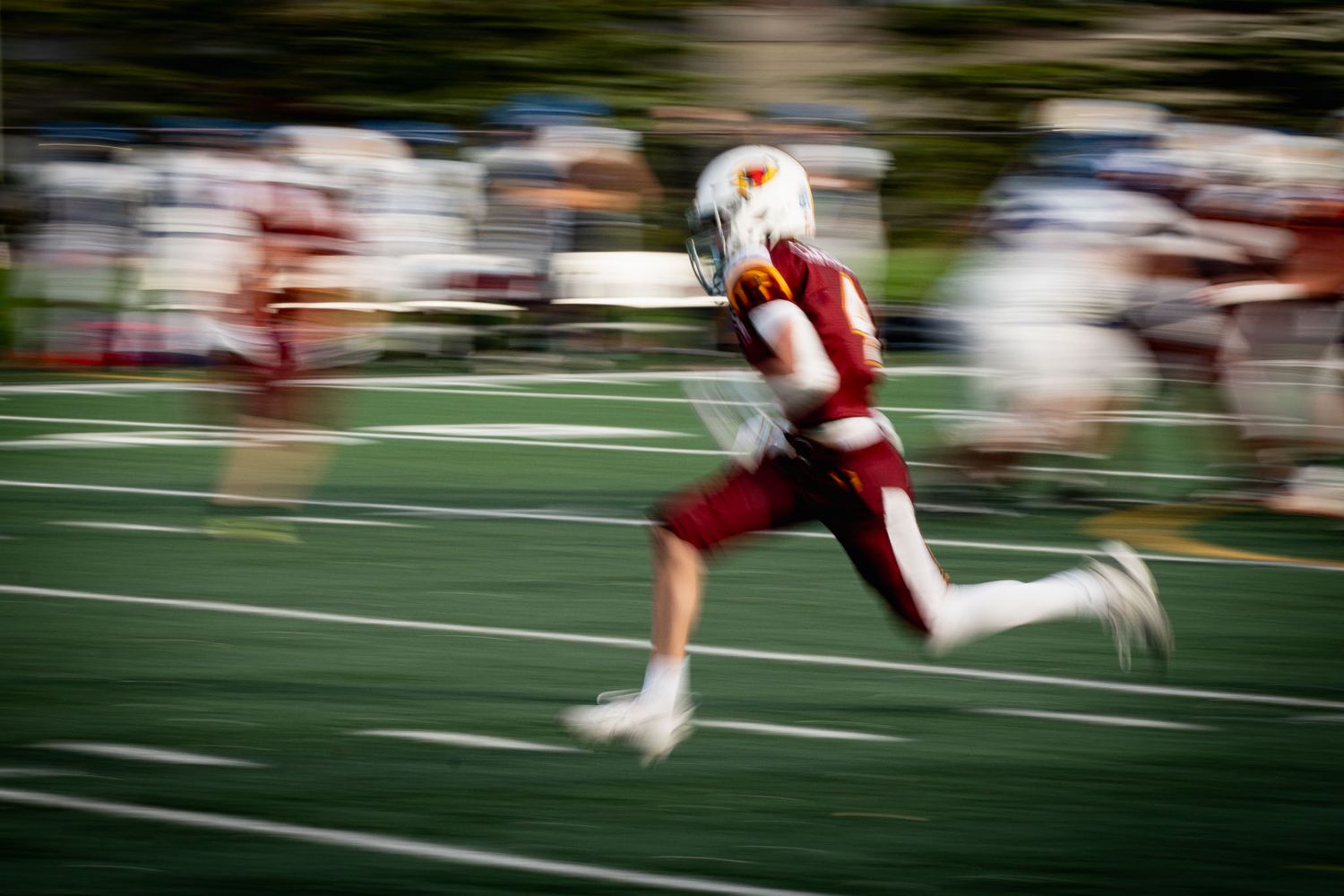 Dynamic football action shot with motion blur effect showing players in white and maroon uniforms.