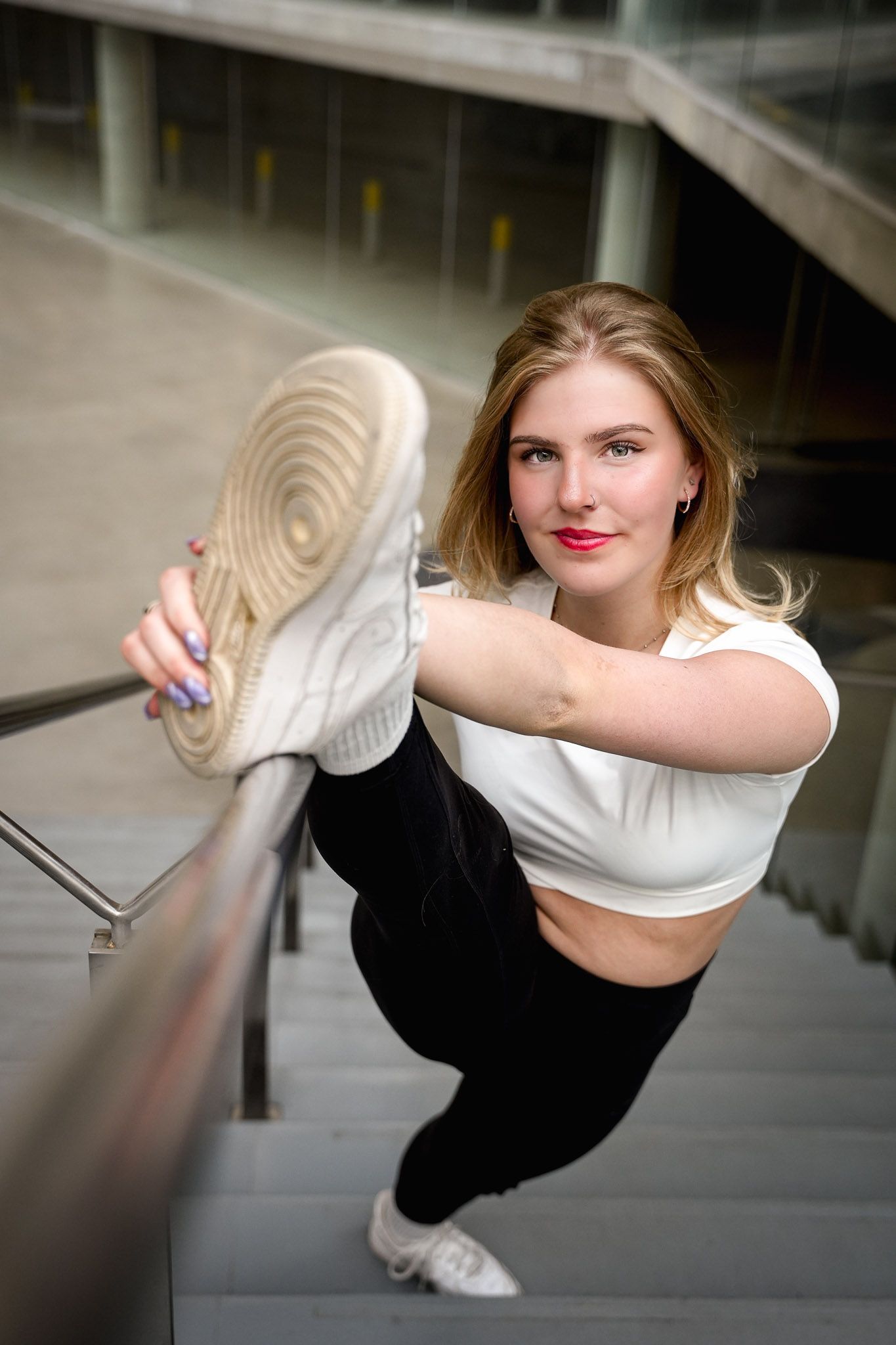 Dancer performing expressive movements along a mirrored wall in white top and black pants.