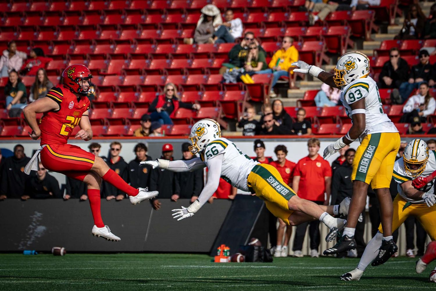 Football game action shot with players in red and yellow uniforms competing on field.