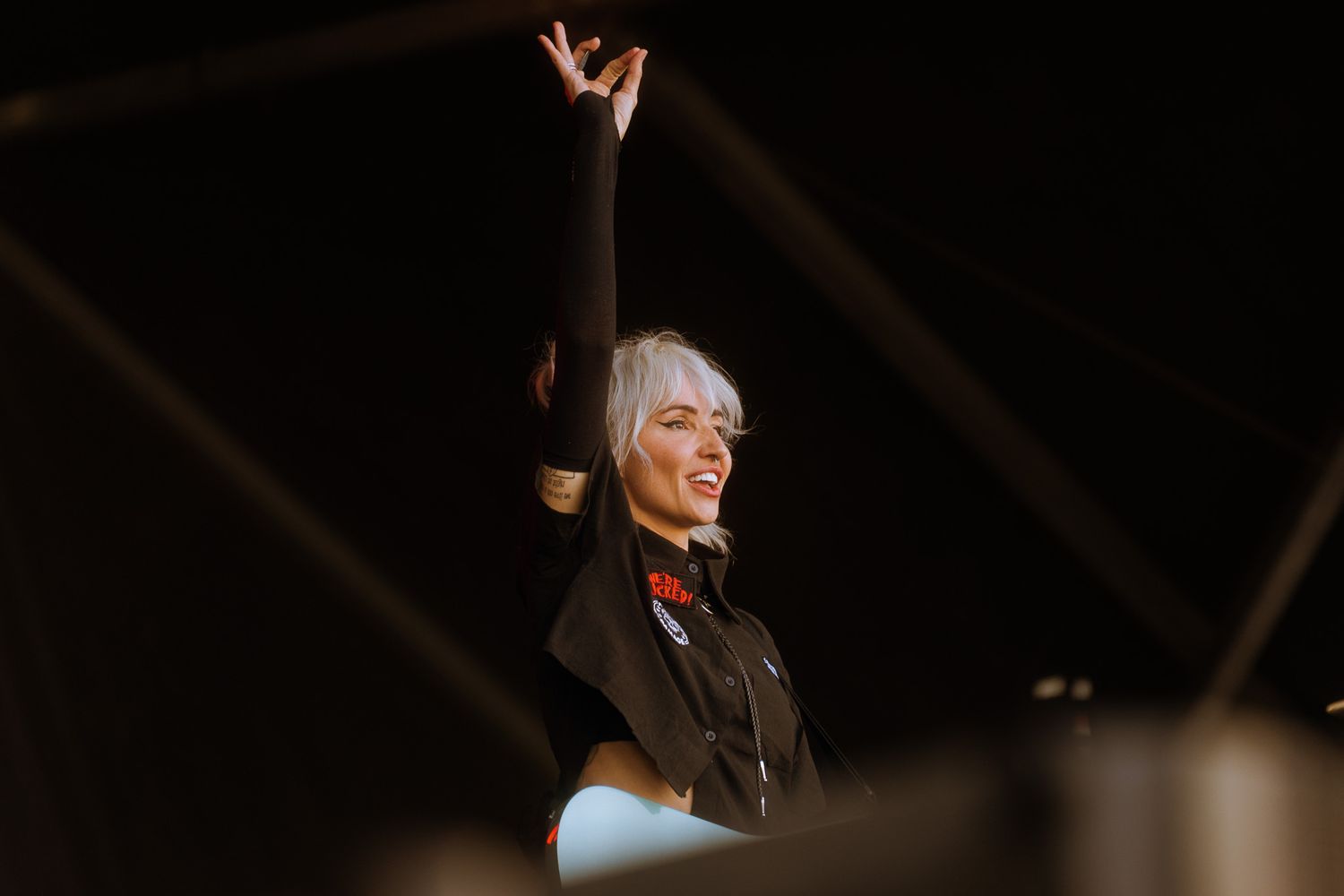 Concert performer raises arms during emotional moment on darkened stage.