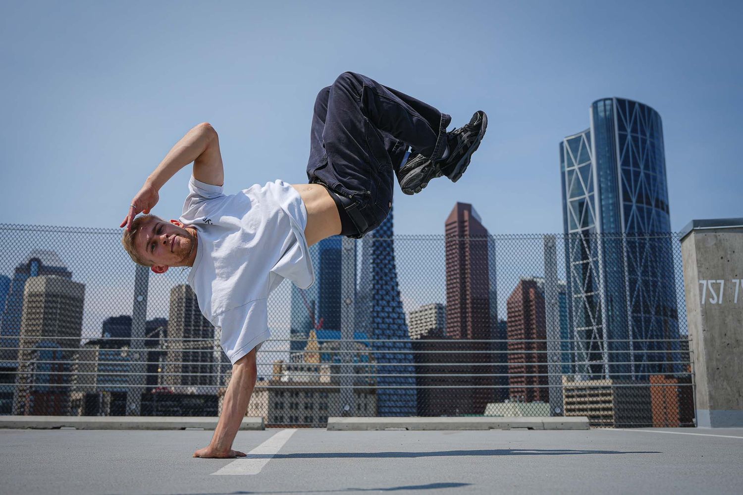 Athletic figure performs handstand against backdrop of modern city skyline.