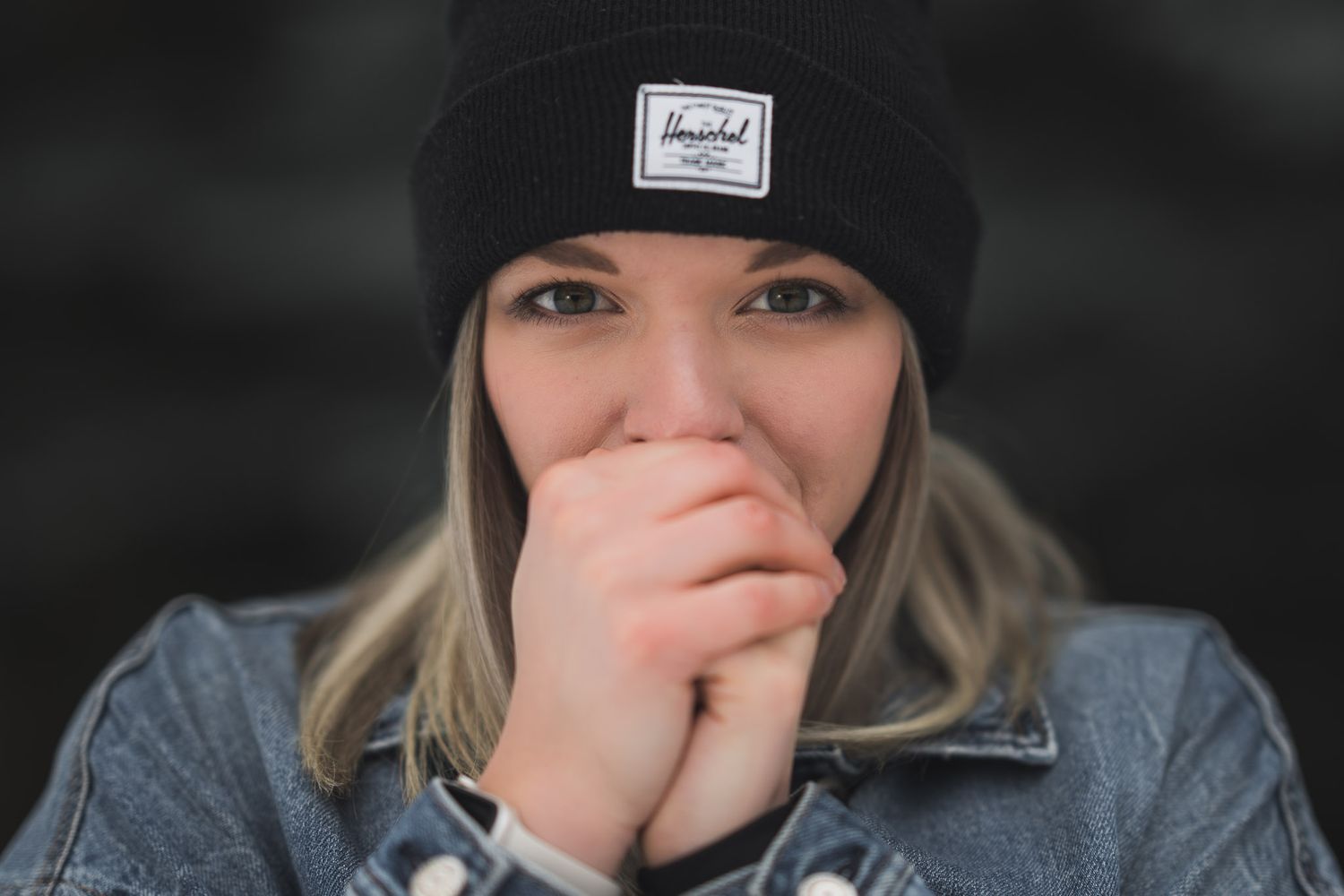 Winter portrait series featuring black beanie and denim jacket against dark background.