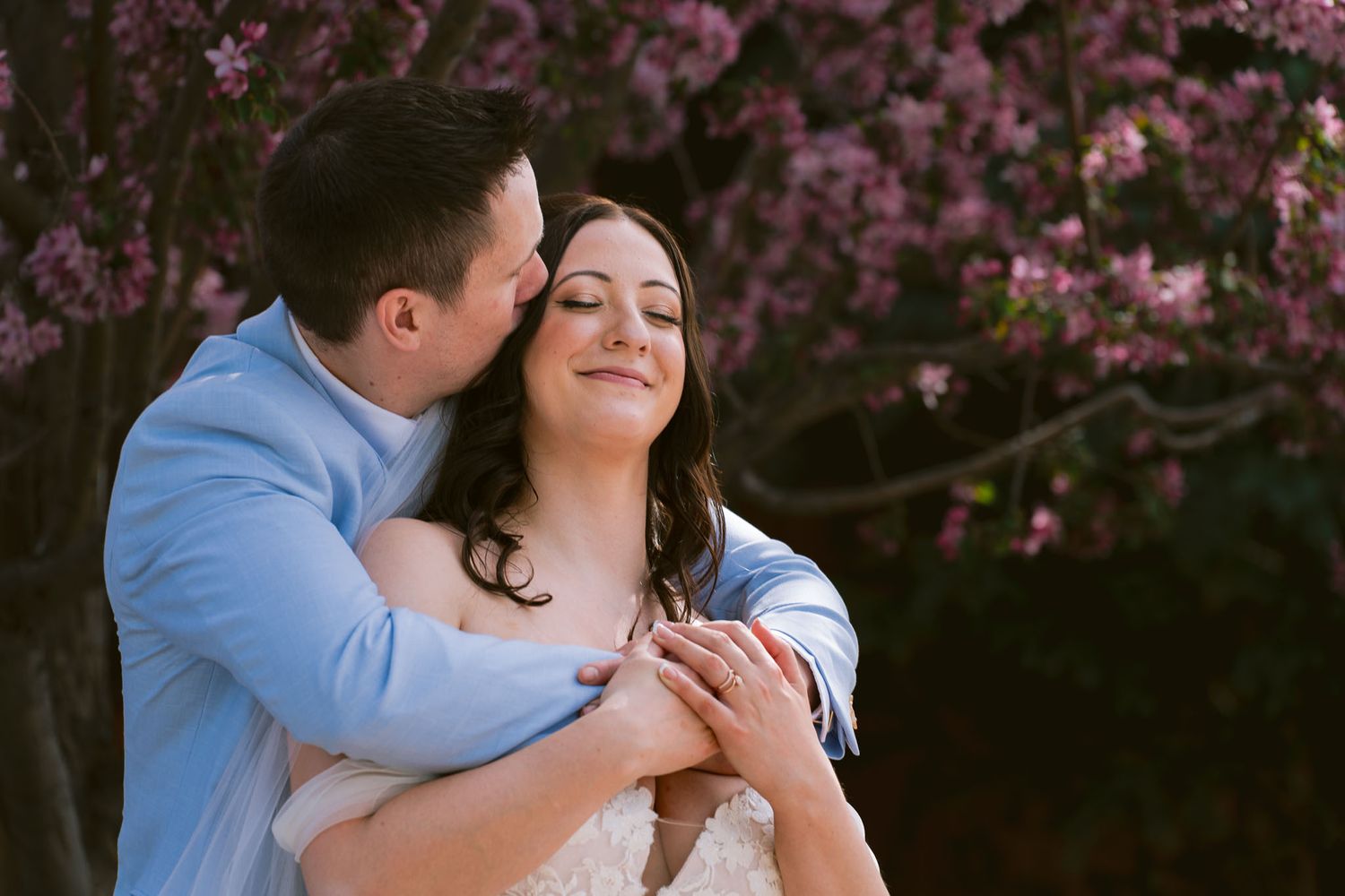 Romantic moments captured against blooming pink cherry blossoms in spring.