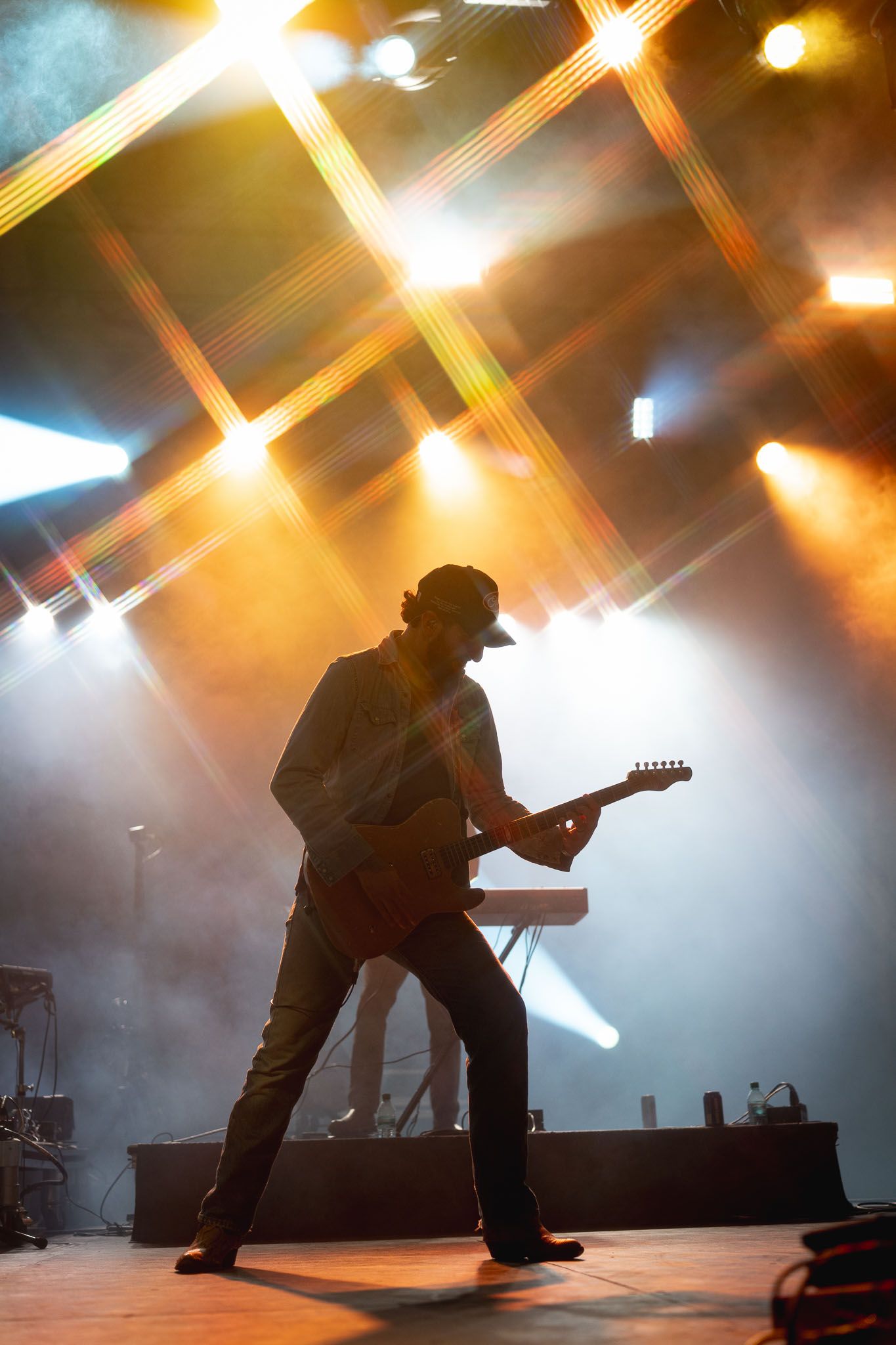 Band members silhouetted against bright orange stage lights during an energetic performance.