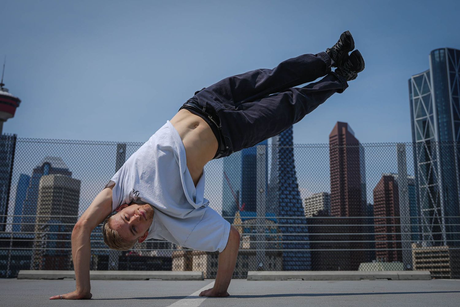 Urban parkour athlete performs acrobatic moves with city skyline backdrop.
