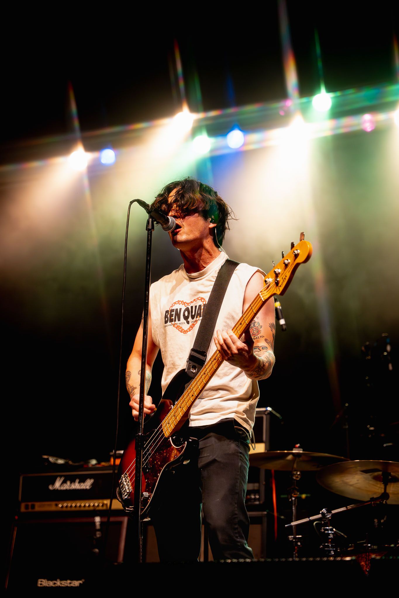 Musicians performing with electric guitars under green and white stage lighting.