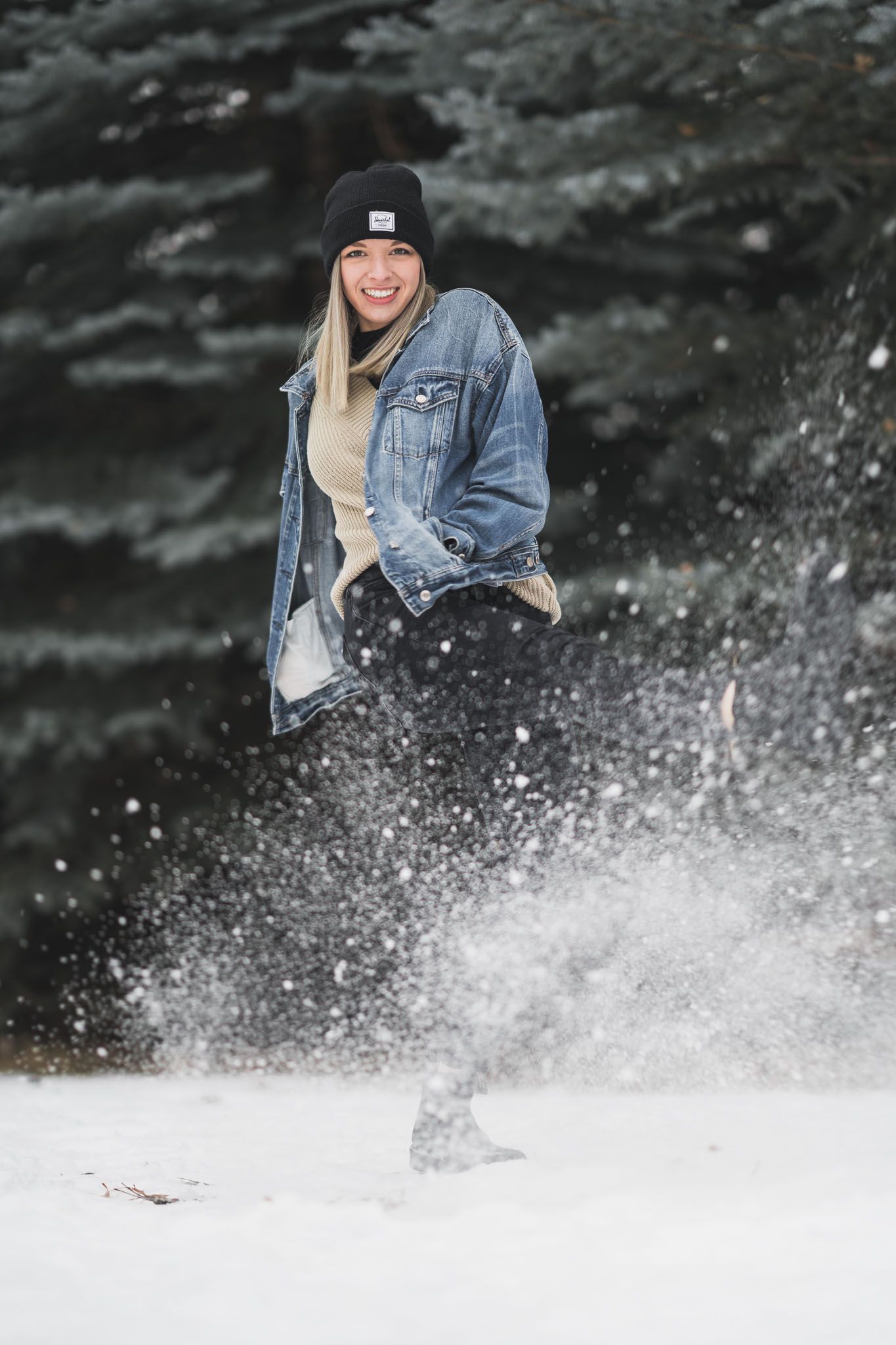 Playful winter scene of someone enjoying snow spray while wearing denim jacket.