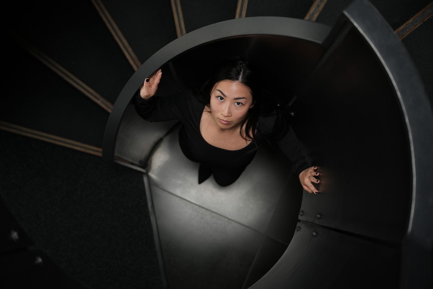 Bird's eye view of a person sitting in a dark circular space with geometric patterns.