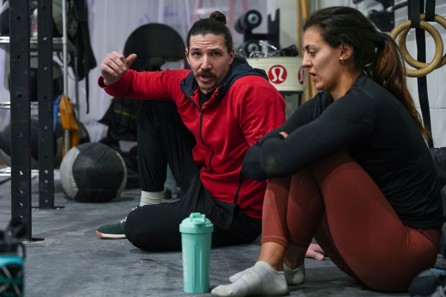 Athletes resting between workout sets in a CrossFit gym setting.