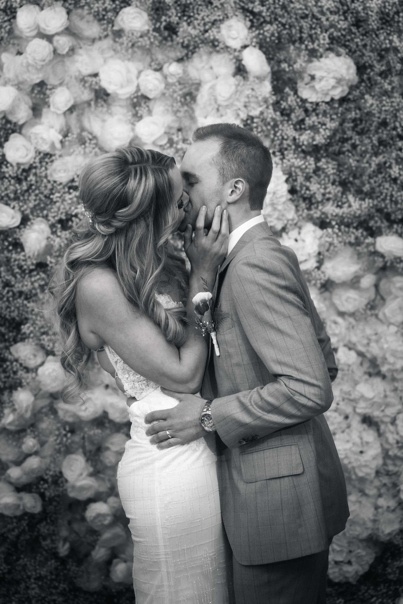 Black and white romantic portrait against a textured backdrop with dramatic lighting.