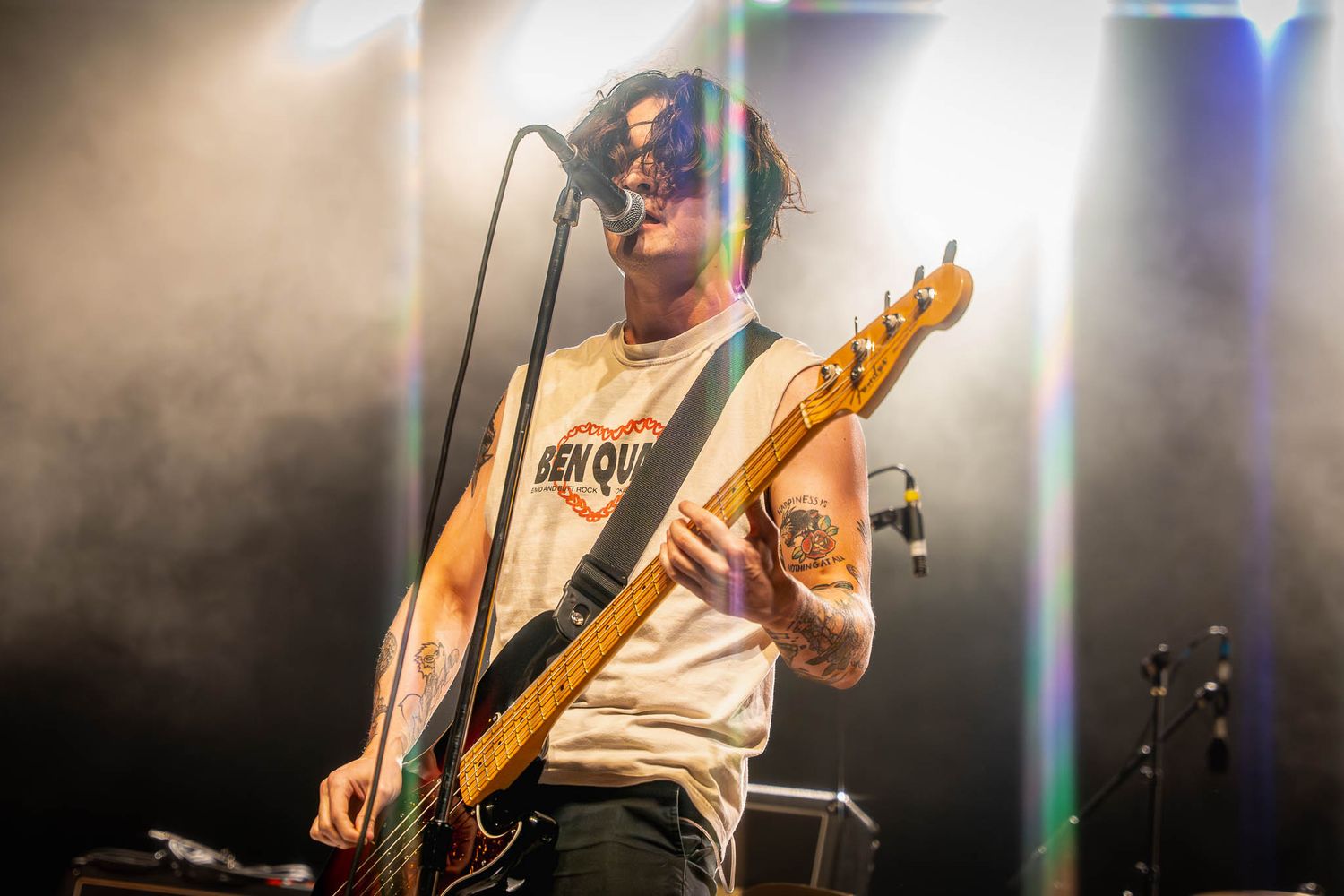 Band member for Mattstagraham playing bass guitar on stage with atmospheric lighting effects.