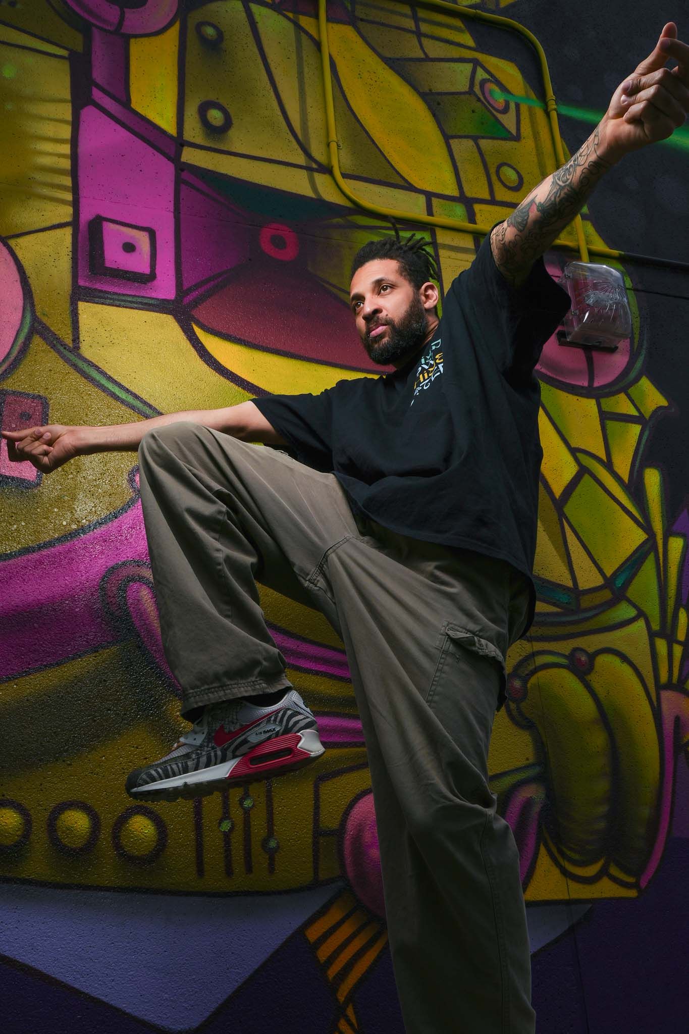 Dancer demonstrates high-energy moves against colorful urban graffiti background.