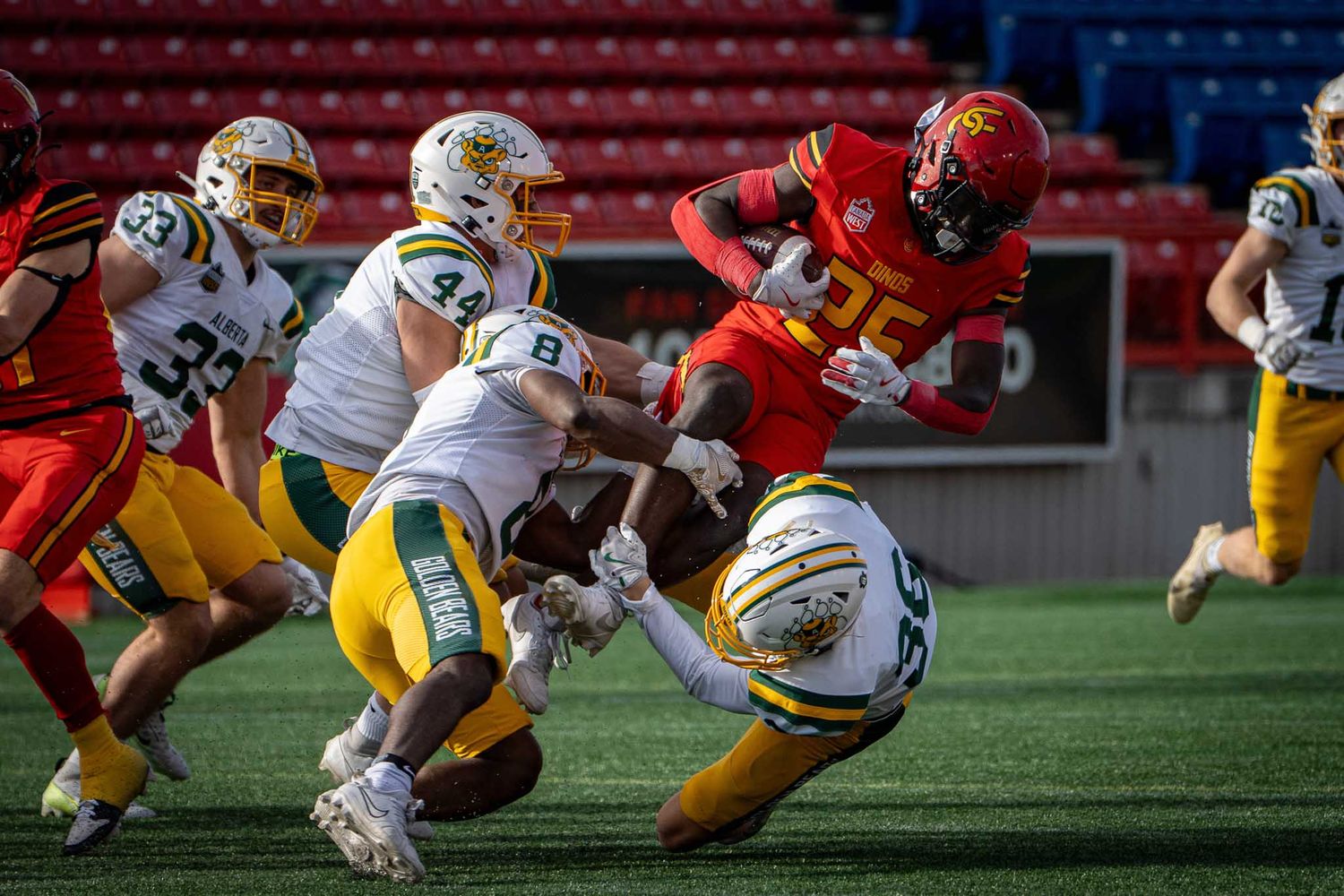 Football players in red and gold uniforms diving and tackling during intense game action.