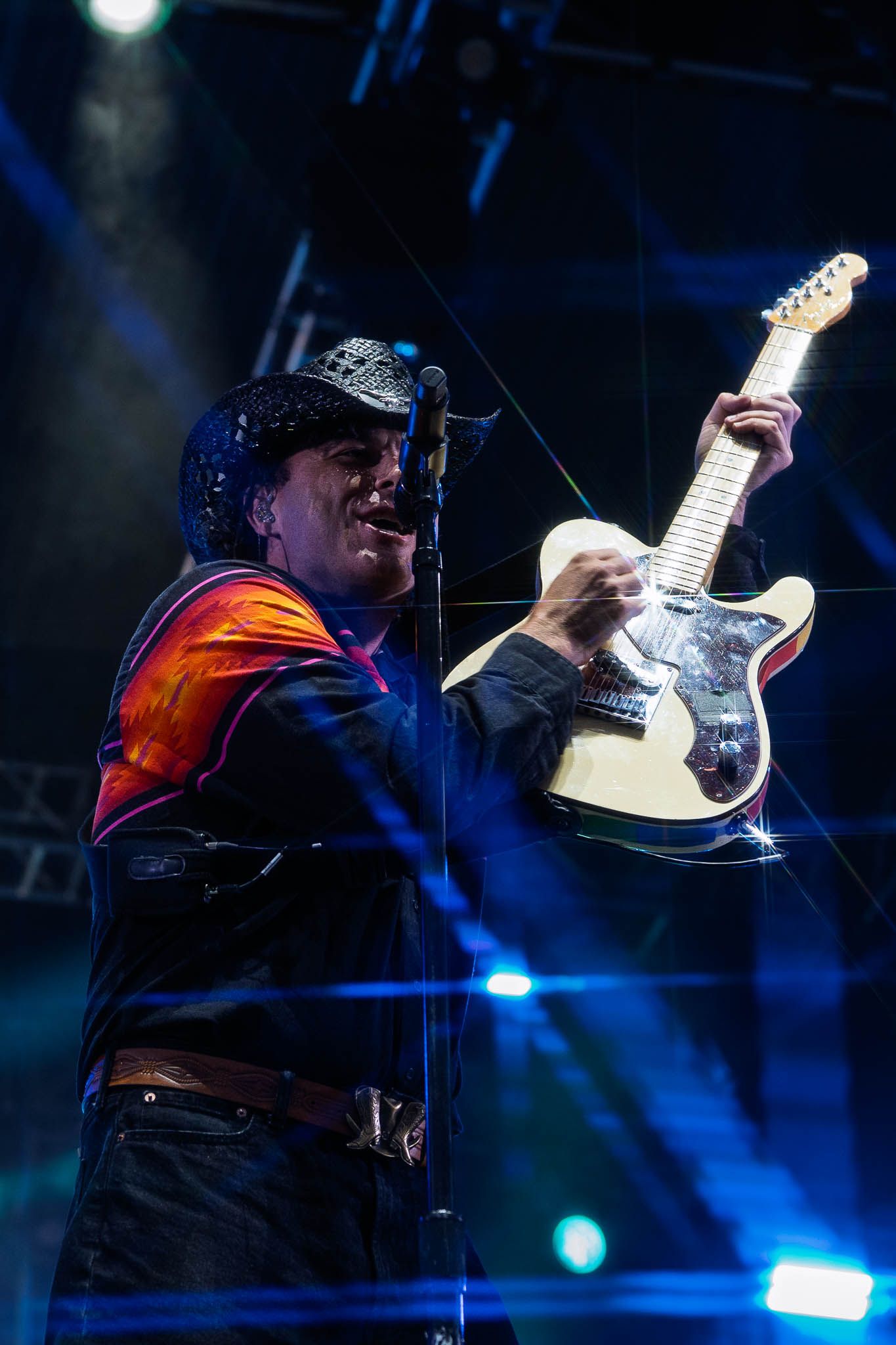 Guitarist performing on stage with blue lighting effects.