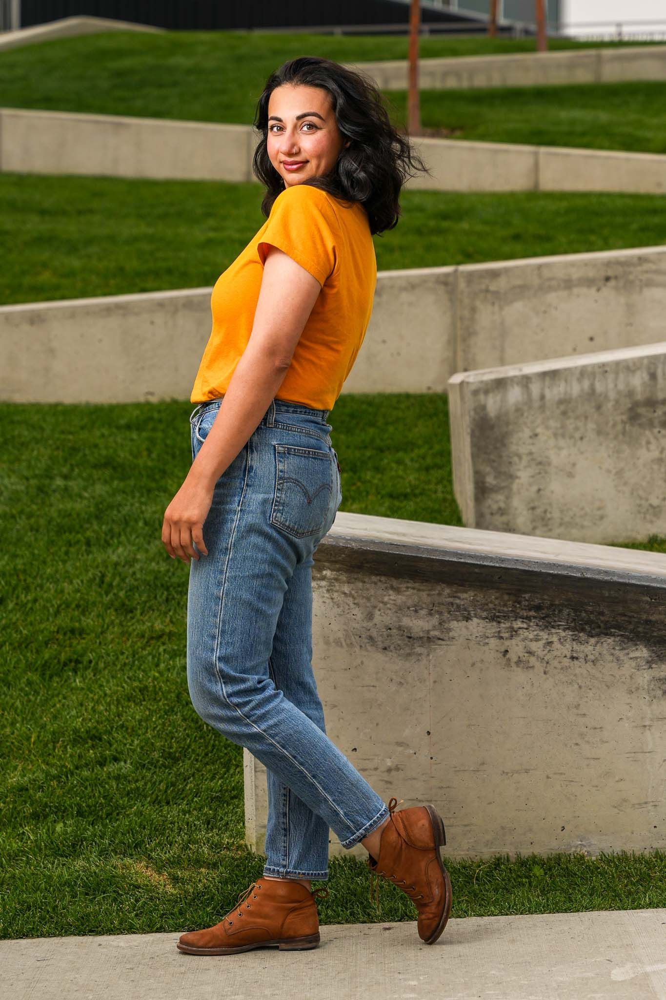 Bright orange t-shirt paired with blue jeans against modern concrete architecture.