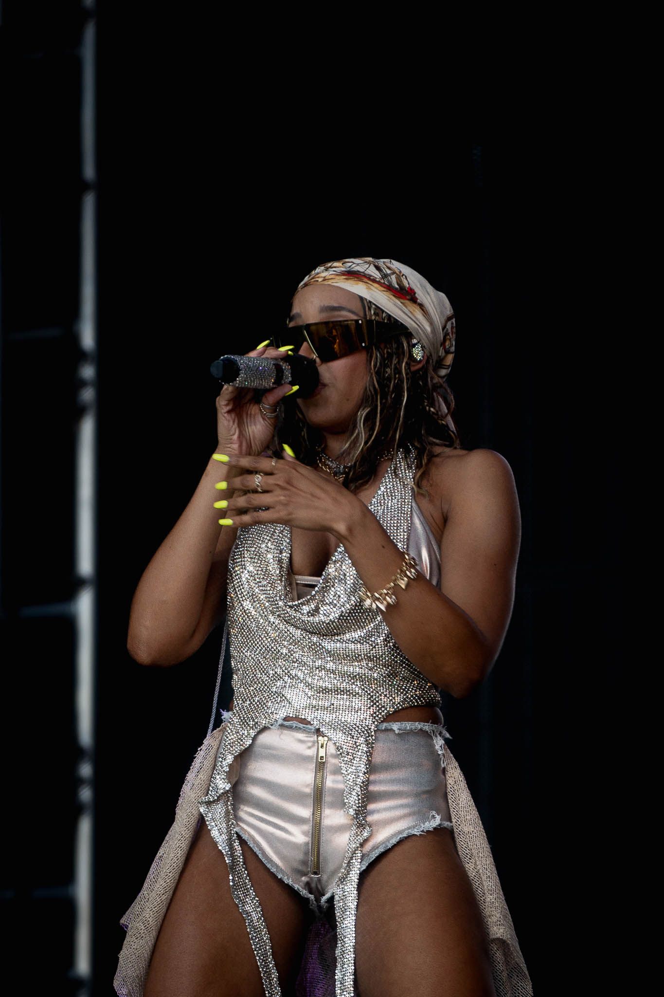 Dancer in glittering silver costume performs expressive movements during stage show.