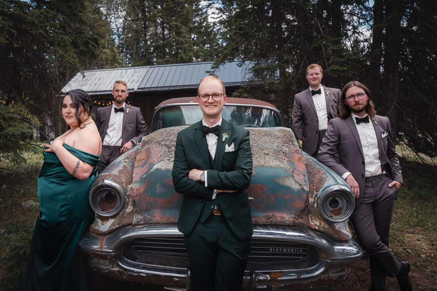 Wedding party poses near vintage car in forest setting outside the grooms suite at The Valley Weddings