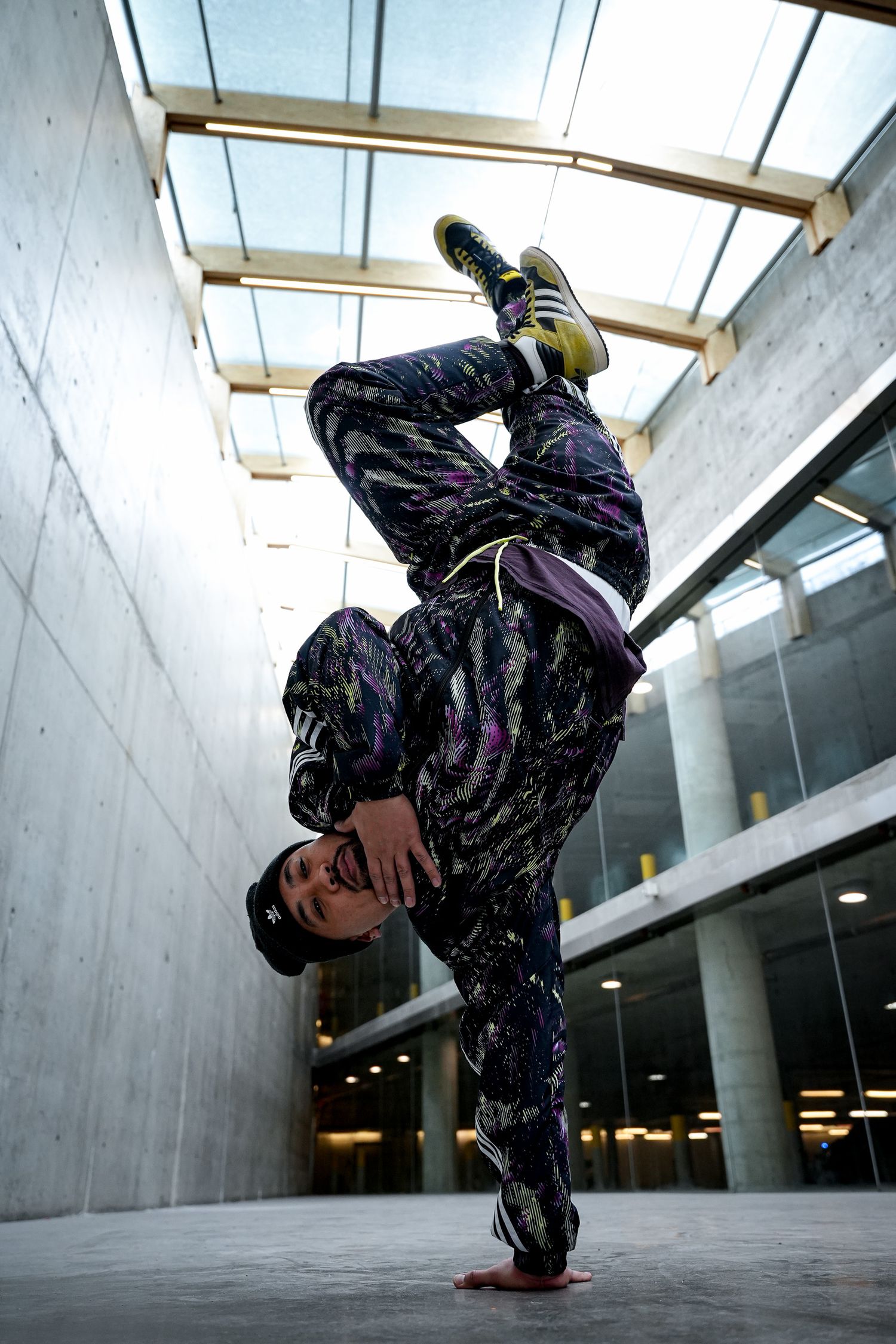 Dancer performs dynamic breakdancing moves in an urban concrete space with dramatic lighting.
