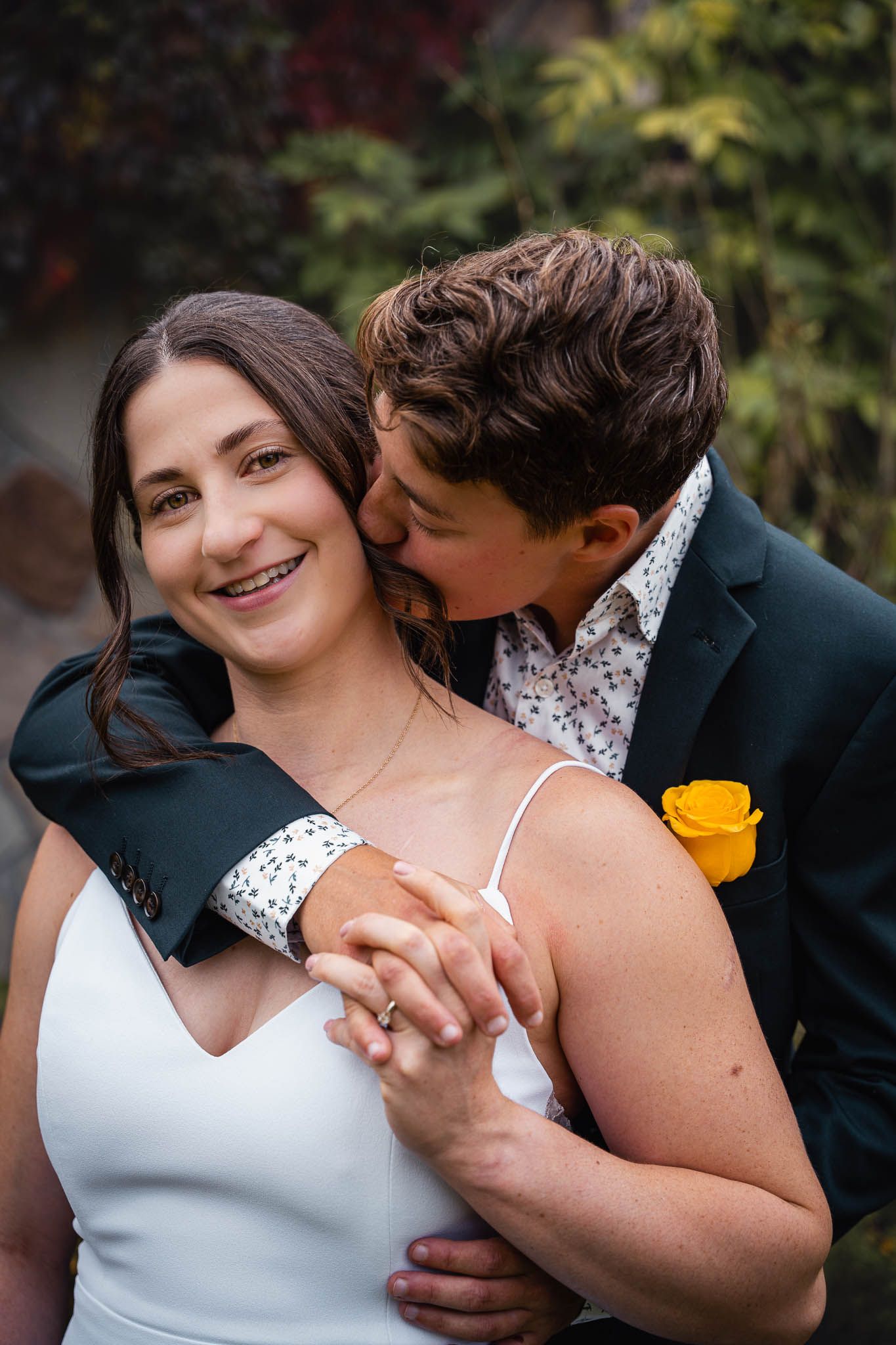 Intimate wedding portraits captured in a garden setting with yellow flower accents.