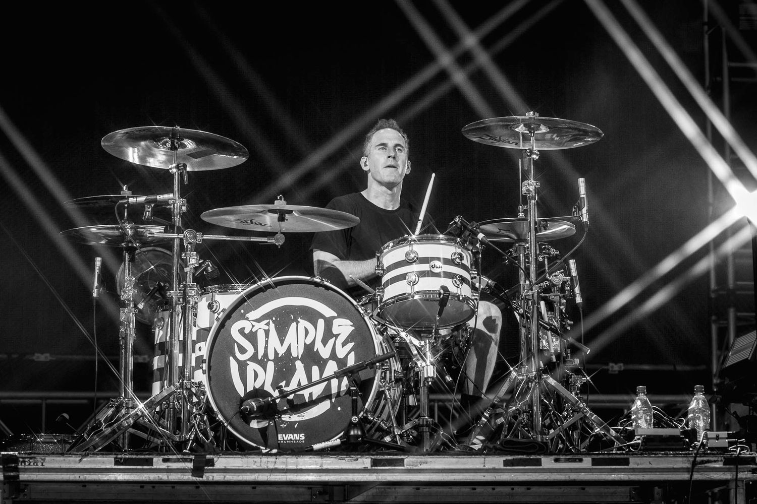 Drummer for Simple Plan silhouetted against dramatic concert lighting.