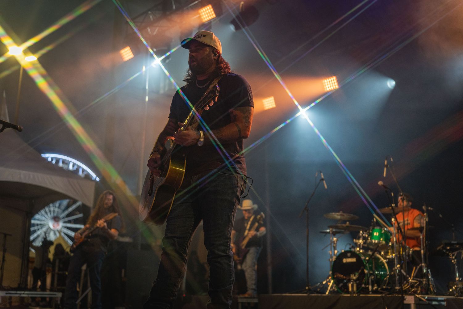 Koe Wetzel on concert stage illuminated with colorful spotlights and lens flares during a live performance.