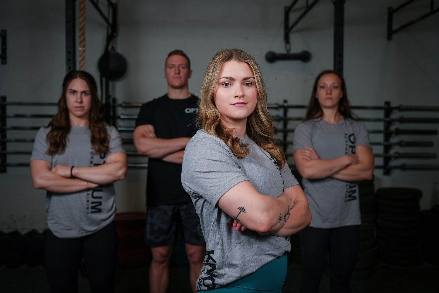Group of athletes posing in athletic stance against dark gym background.