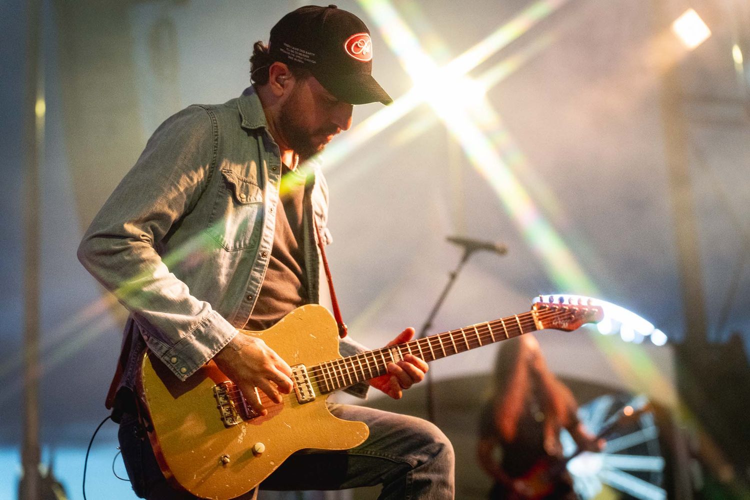 Electric and acoustic guitarists performing under bright stage lighting.
