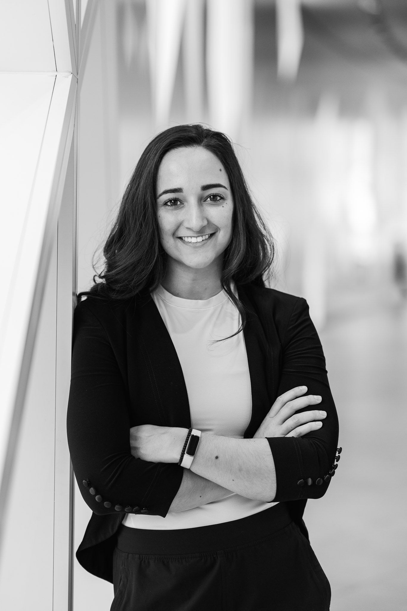 Professional portrait series showing person in black blazer against bright hallway.