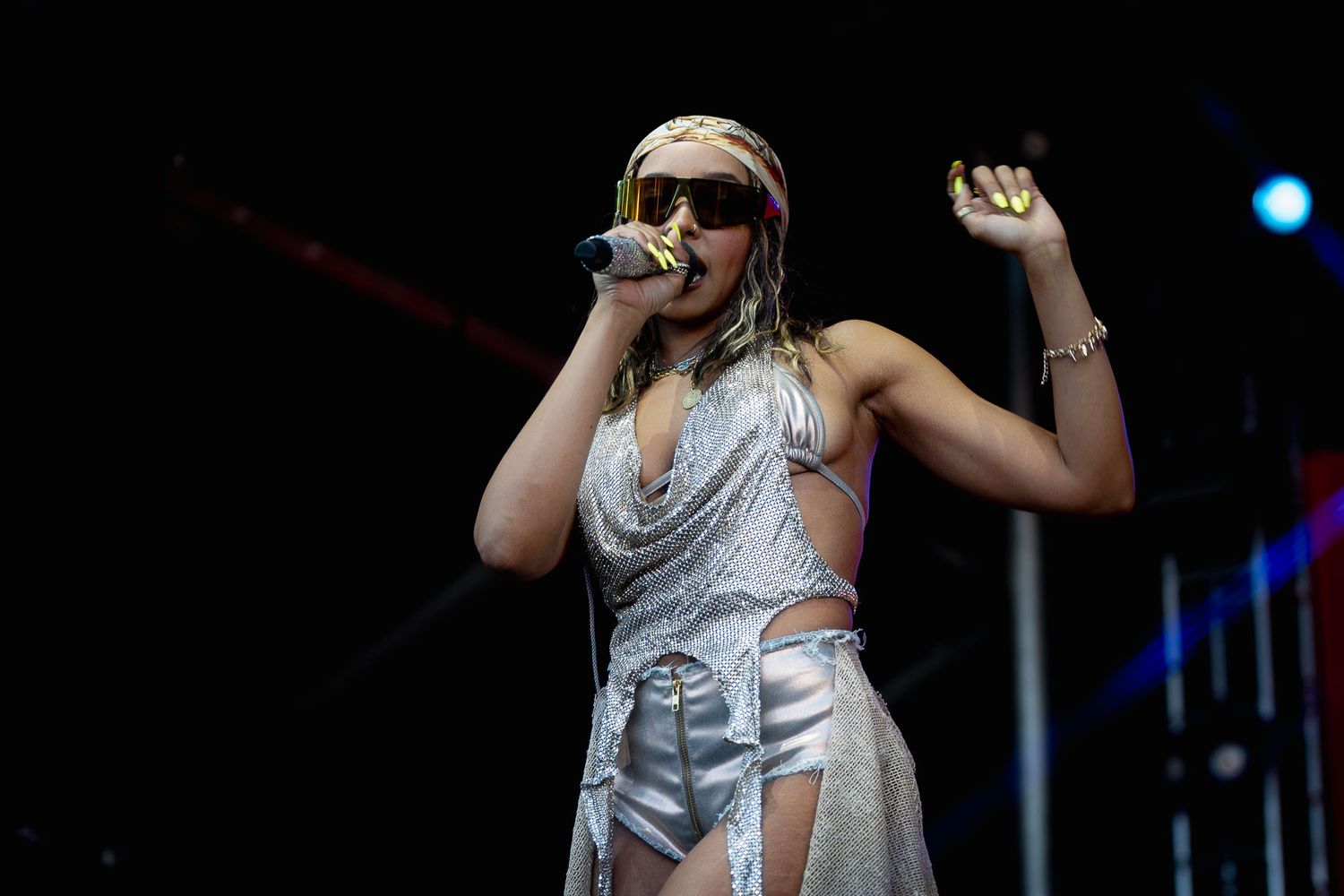 Tinashe in shimmering silver outfit dancing on stage during live show.