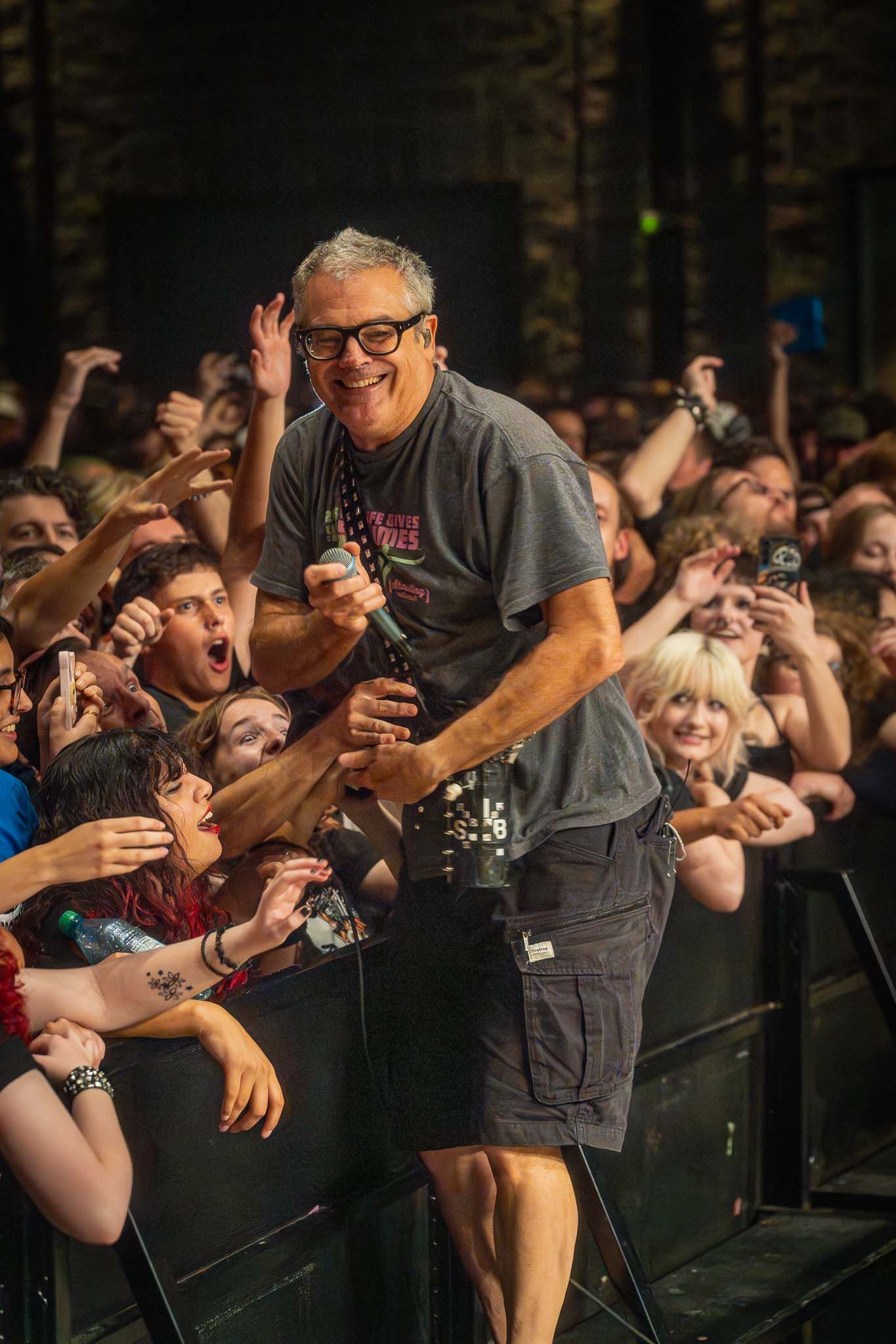 The Descendents interacting with enthusiastic crowd reaching out from the front row.