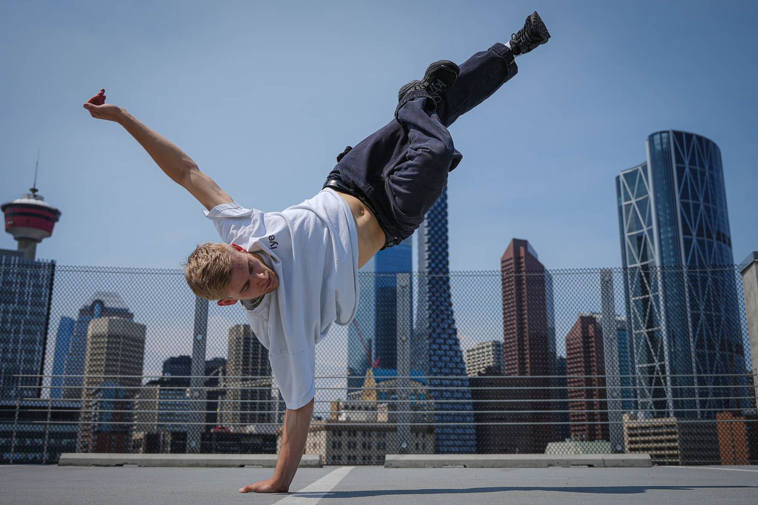Acrobatic dancer executes handstand with city skyscrapers in background.